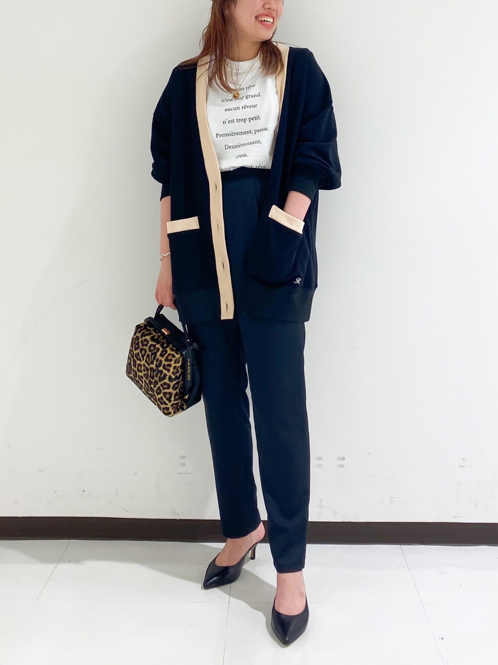 ブラウン系のショルダーバッグ、ブラック系のパンプス、ホワイト系のTシャツ/カットソーを着用したレディースの秋コーディネートの2枚目の写真