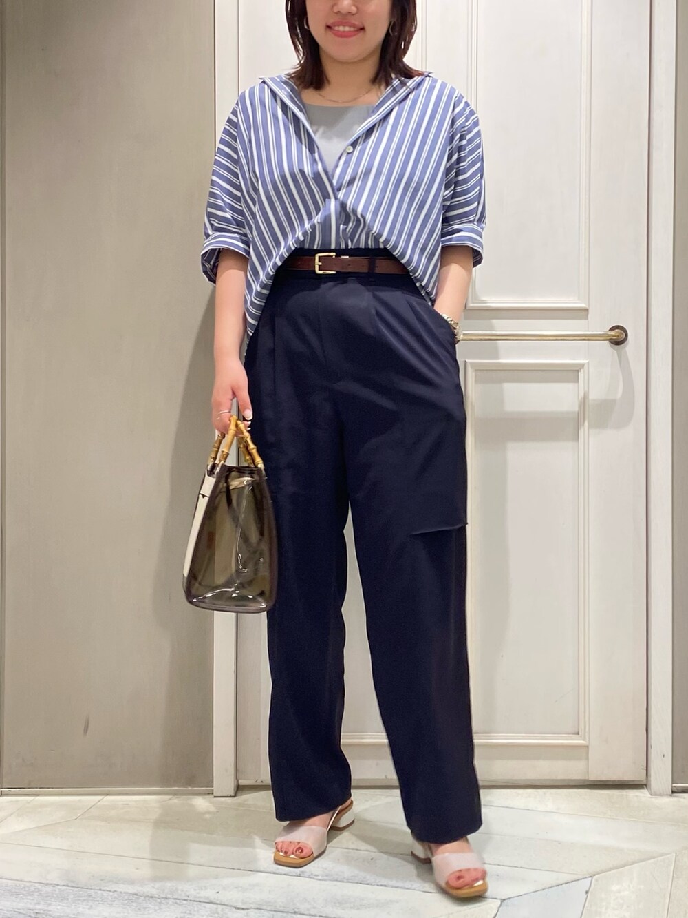 ブラウン系のトートバッグ、ホワイト系のサンダル、ブルー系のその他パンツを着用したレディースの夏コーディネートの3枚目の写真