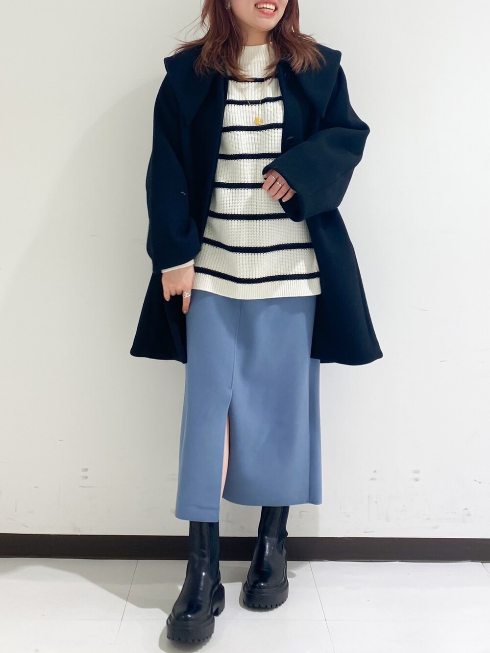 ブラック系のチェスターコート、ブラック系のブーツ、ブルー系のスカートを着用したレディースの冬コーディネートの3枚目の写真