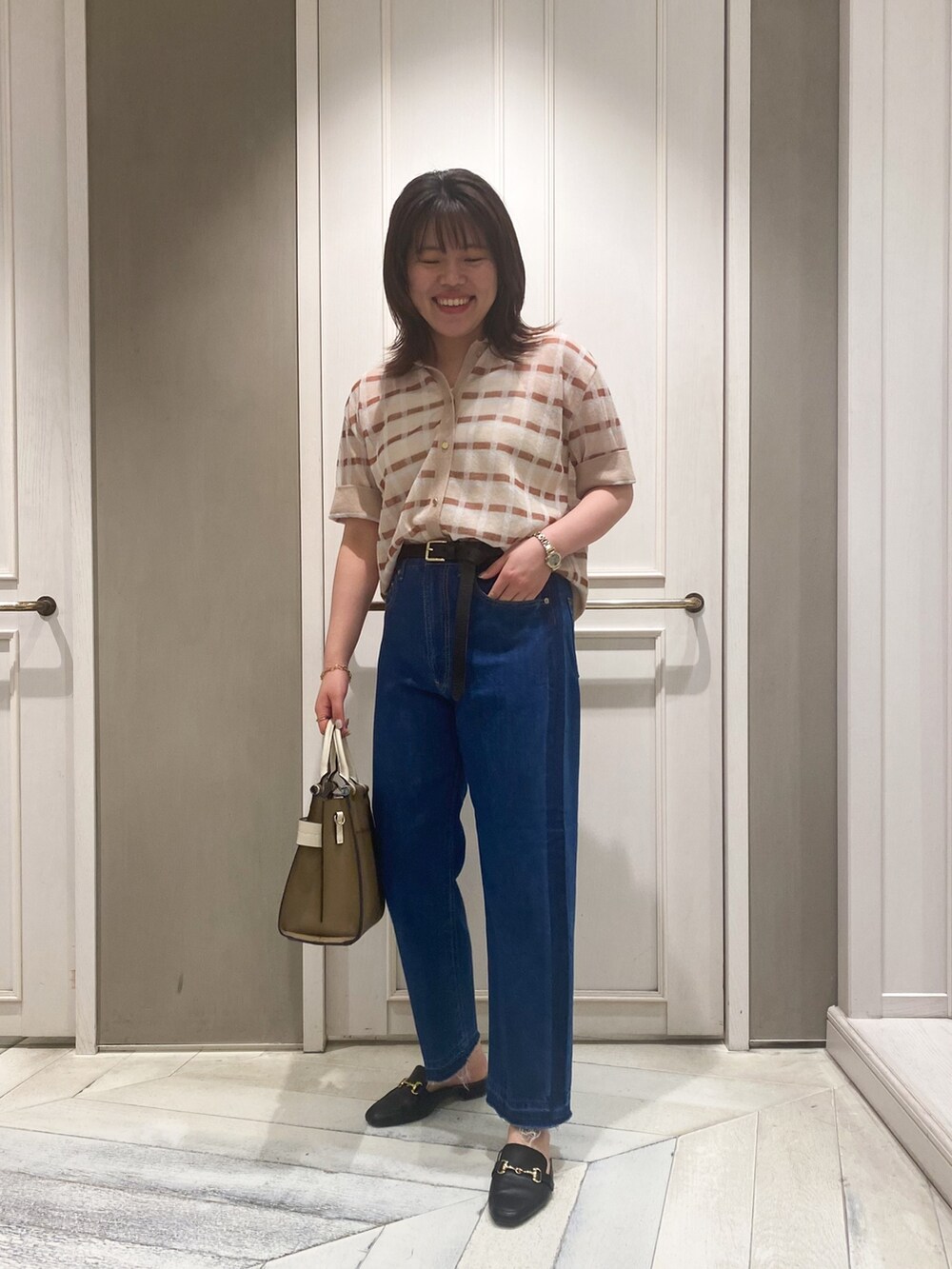 ベージュ系のニット/セーター、ベージュ系のショルダーバッグ、ブルー系のデニムパンツを着用したレディースの春コーディネートの3枚目の写真