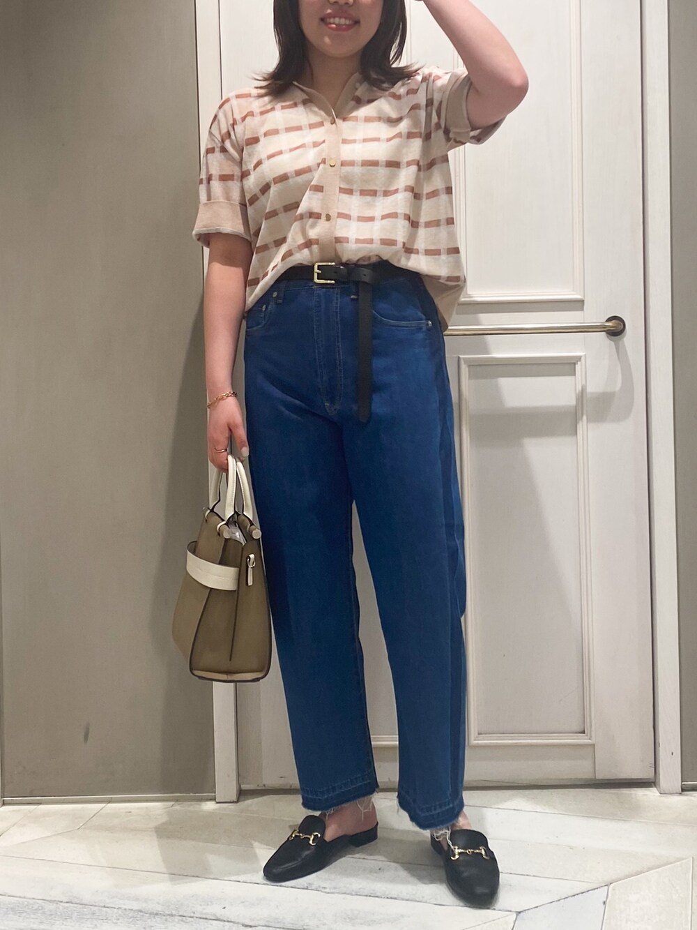 ベージュ系のニット/セーター、ベージュ系のショルダーバッグ、ブルー系のデニムパンツを着用したレディースの春コーディネートの6枚目の写真