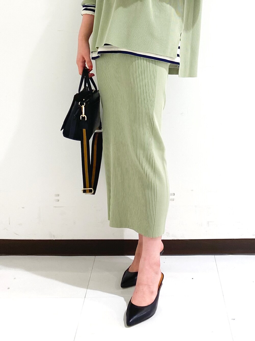 グリーン系のニット/セーター、グリーン系のスカート、ブラウン系のハンドバッグを着用したレディースの秋コーディネートの3枚目の写真