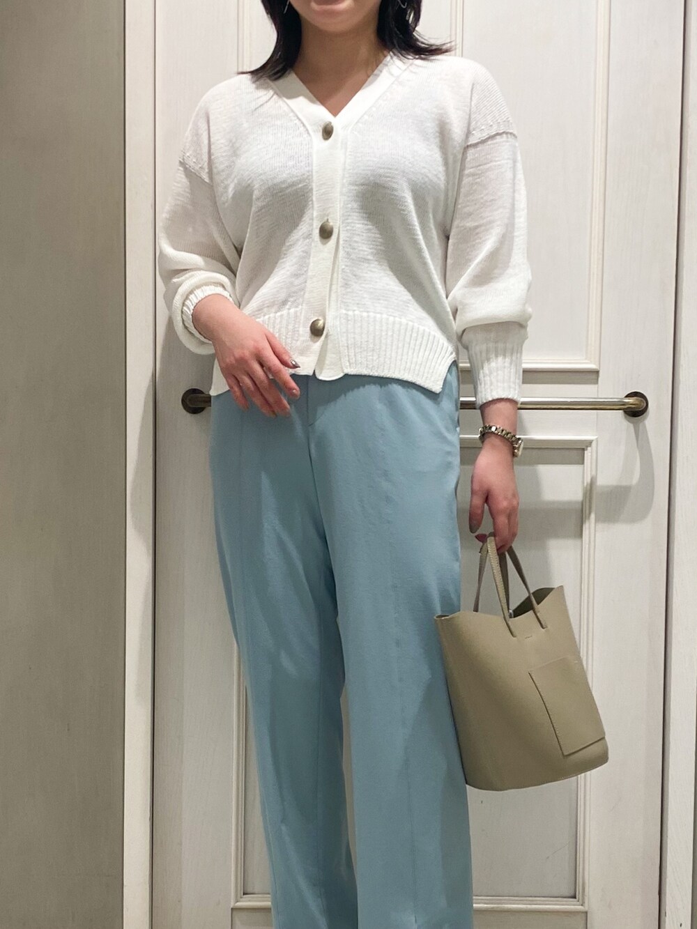 ホワイト系のカーディガン/ボレロ、ベージュ系のハンドバッグ、ブルー系のスラックスを着用したレディースの春コーディネートの4枚目の写真