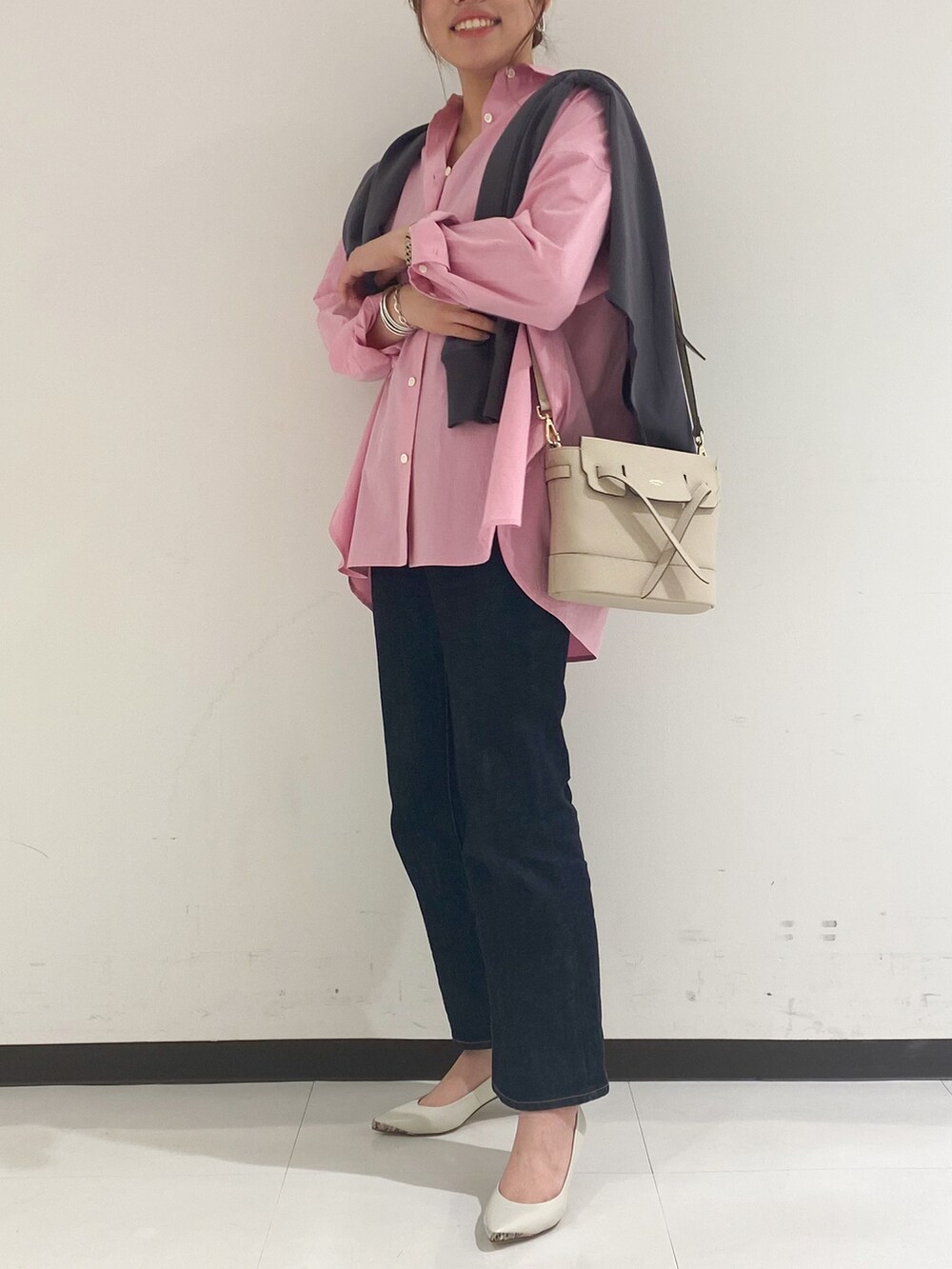 ホワイト系のショルダーバッグ、ブルー系のデニムパンツ、グレー系のパンプスを着用したレディースの春コーディネートの2枚目の写真