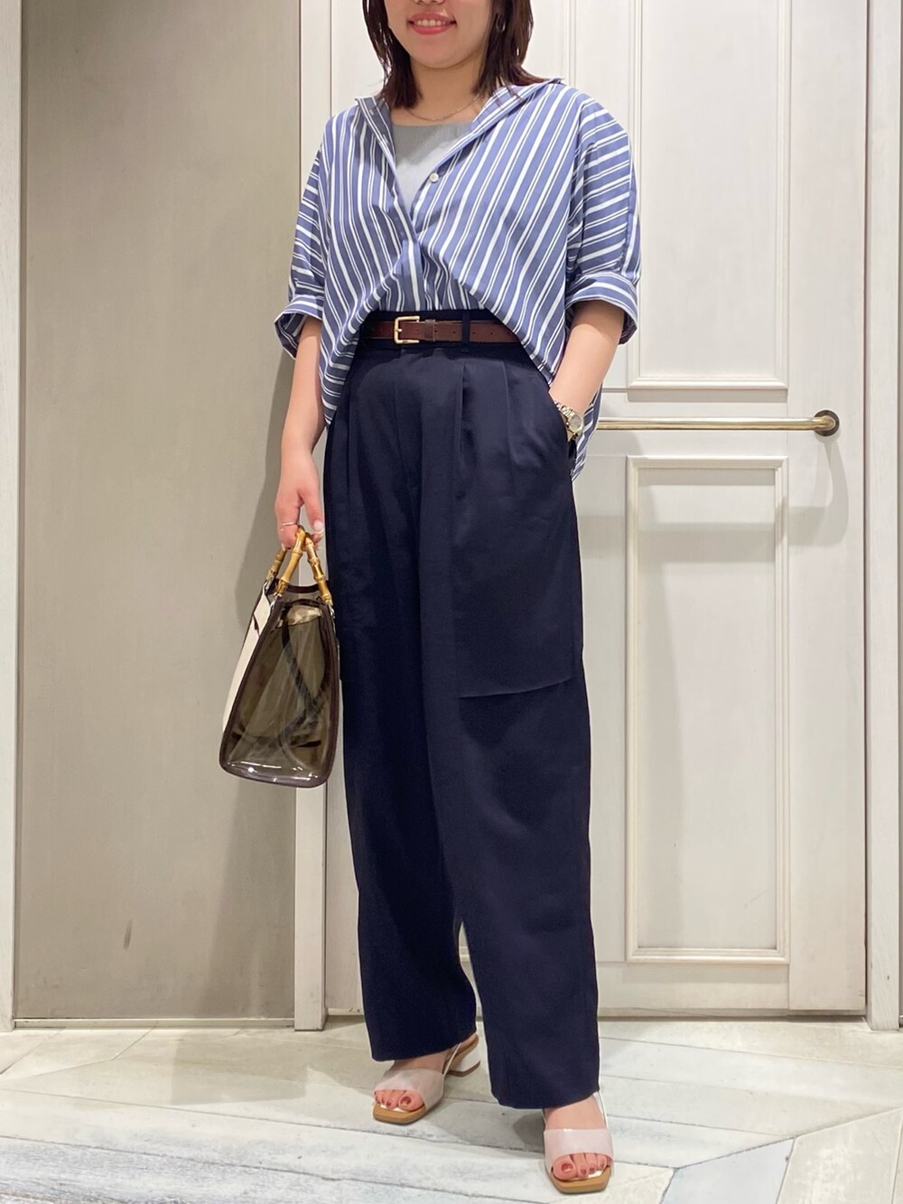 ブラウン系のトートバッグ、ホワイト系のサンダル、ブルー系のその他パンツを着用したレディースの夏コーディネートの4枚目の写真