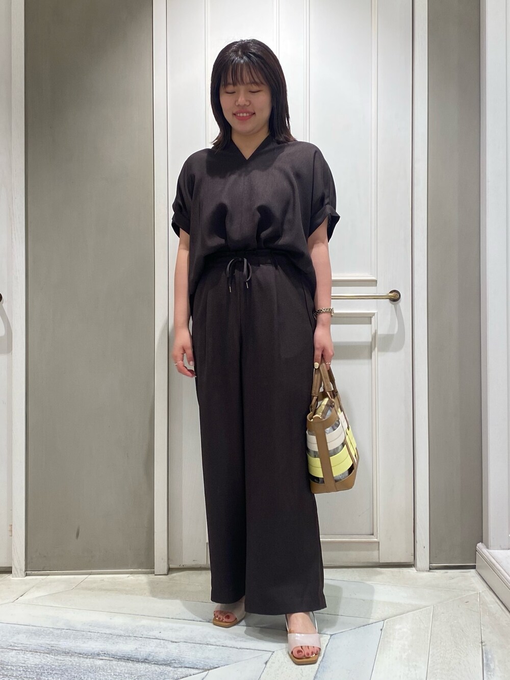 ブラウン系のシャツ/ブラウス、イエロー系のハンドバッグ、ホワイト系のサンダルを着用したレディースの夏コーディネートの2枚目の写真