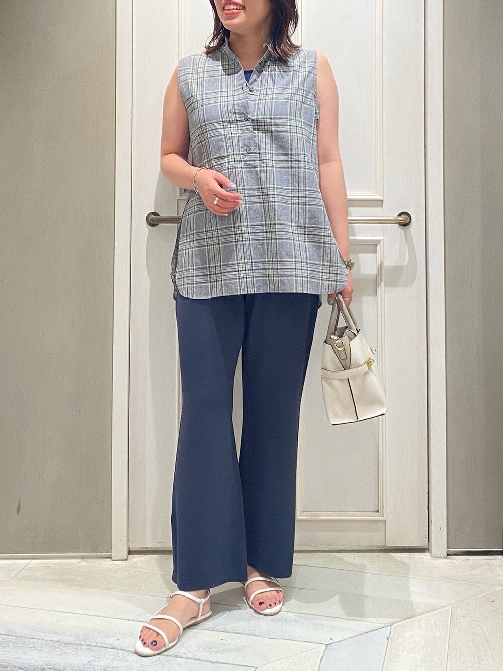 グリーン系のタンクトップ、レッド系のサンダル、ホワイト系のショルダーバッグを着用したレディースの夏コーディネートの3枚目の写真