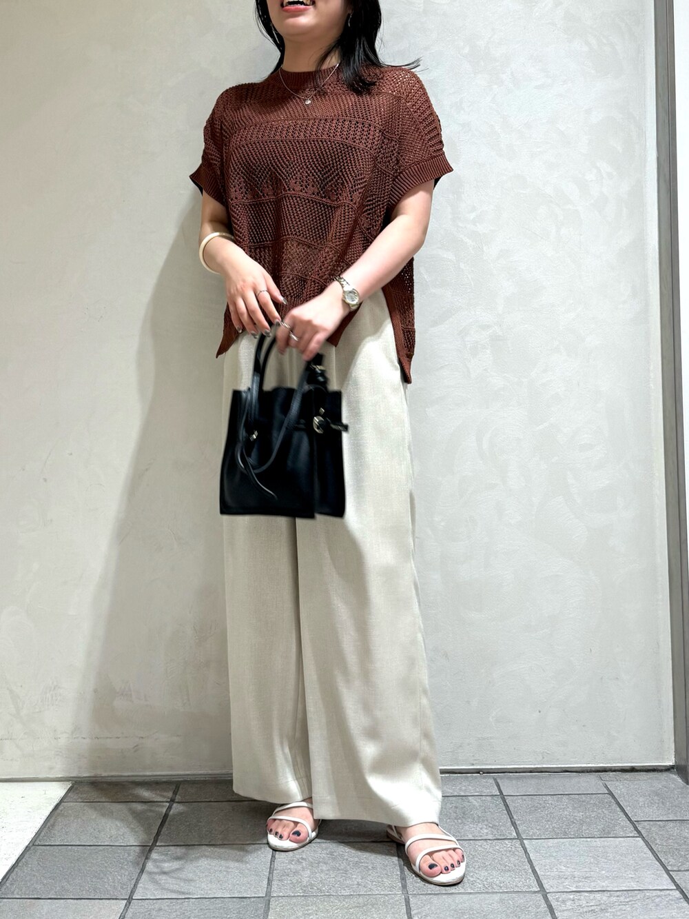 ブラウン系のニット/セーター、ホワイト系のトートバッグを着用したレディースの夏コーディネートの3枚目の写真