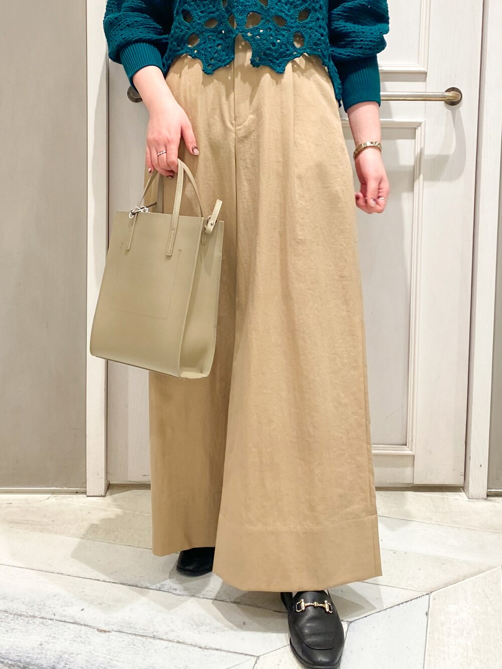 ベージュ系のトートバッグ、ベージュ系のその他パンツ、グリーン系のニット/セーターを着用したレディースの冬コーディネートの2枚目の写真