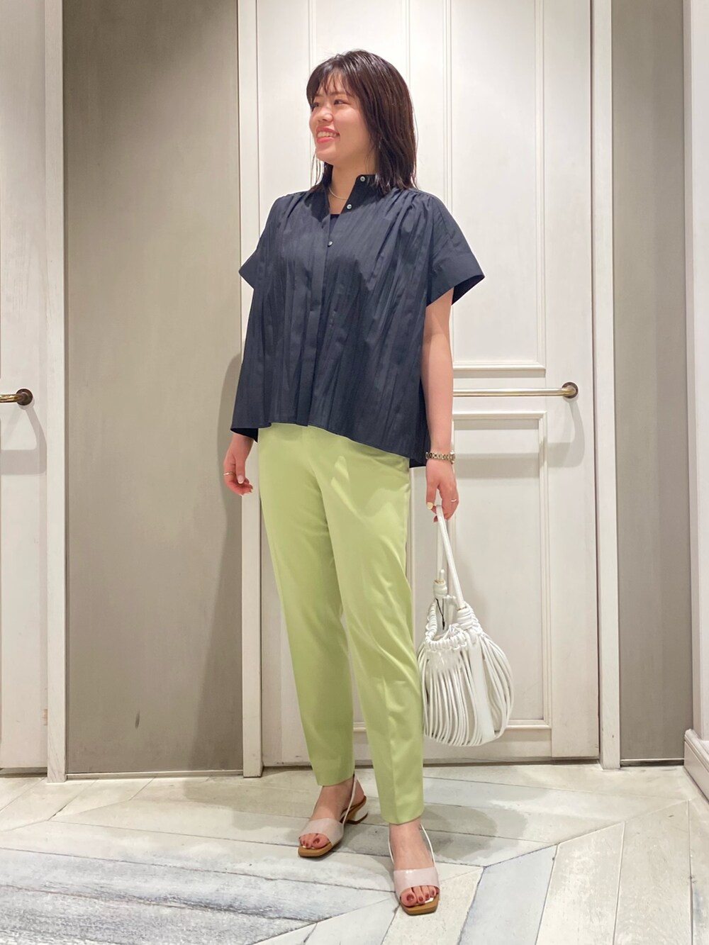 ブラック系のシャツ/ブラウス、グリーン系のスラックス、ホワイト系のサンダルを着用したレディースの夏コーディネートの4枚目の写真