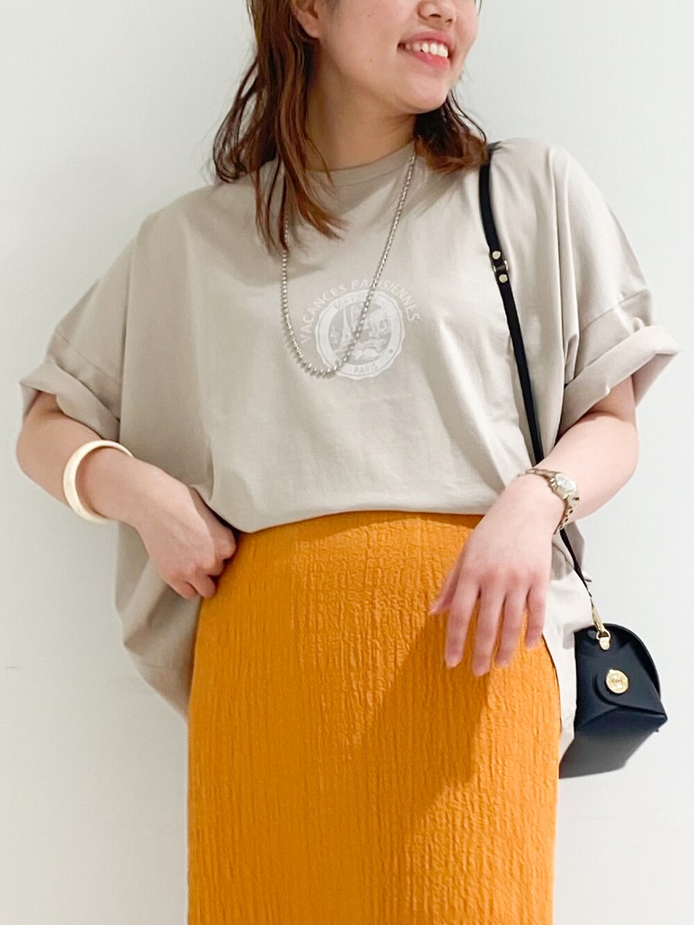 ベージュ系のTシャツ/カットソー、ブラック系のスカート、ブラック系のショルダーバッグを着用したレディースの春コーディネートの3枚目の写真