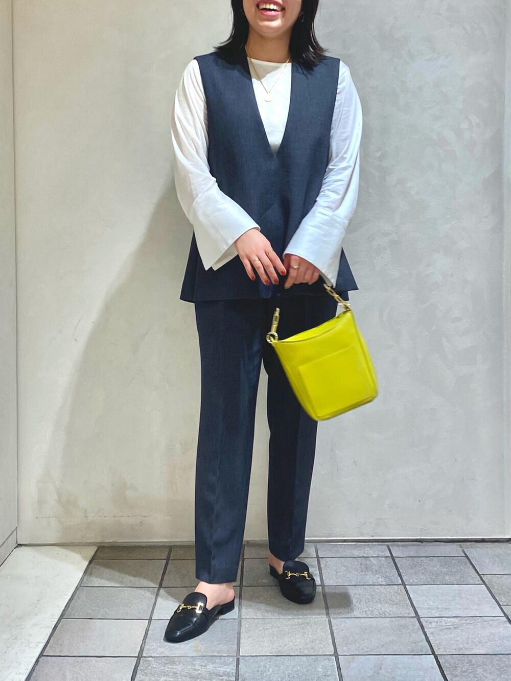 グレー系のベスト、グレー系のスラックス、ホワイト系のTシャツ/カットソーを着用したレディースの秋コーディネートの5枚目の写真