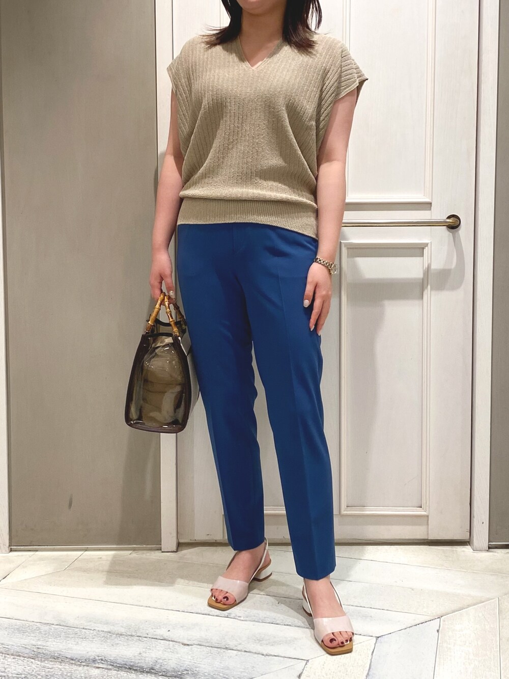 ベージュ系のニット/セーター、ブラウン系のトートバッグ、ブルー系のスラックスを着用したレディースの春コーディネートの2枚目の写真