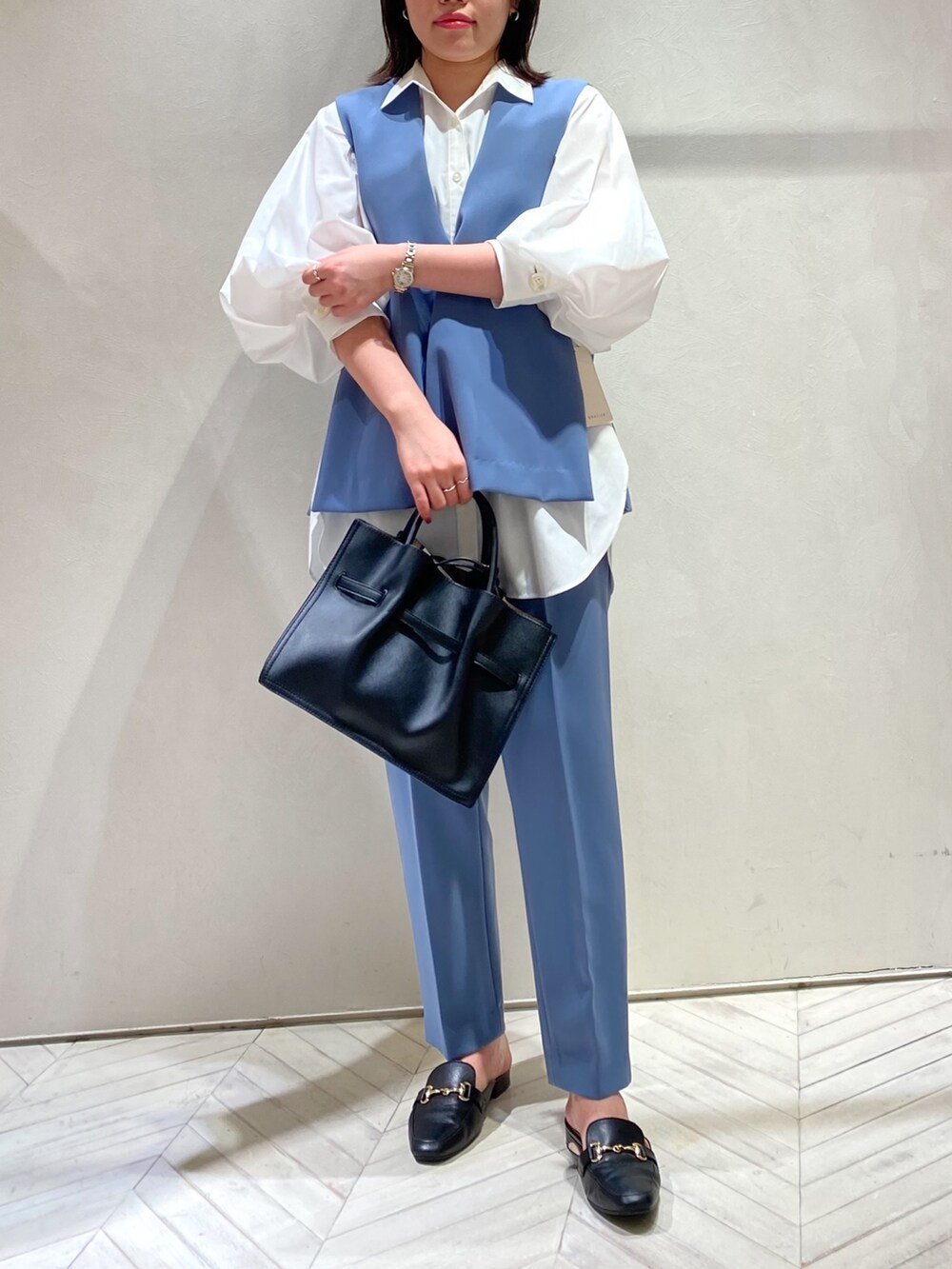 ホワイト系のシャツ/ブラウス、ブラック系のハンドバッグ、ブルー系のスラックスを着用したレディースの秋コーディネートの3枚目の写真