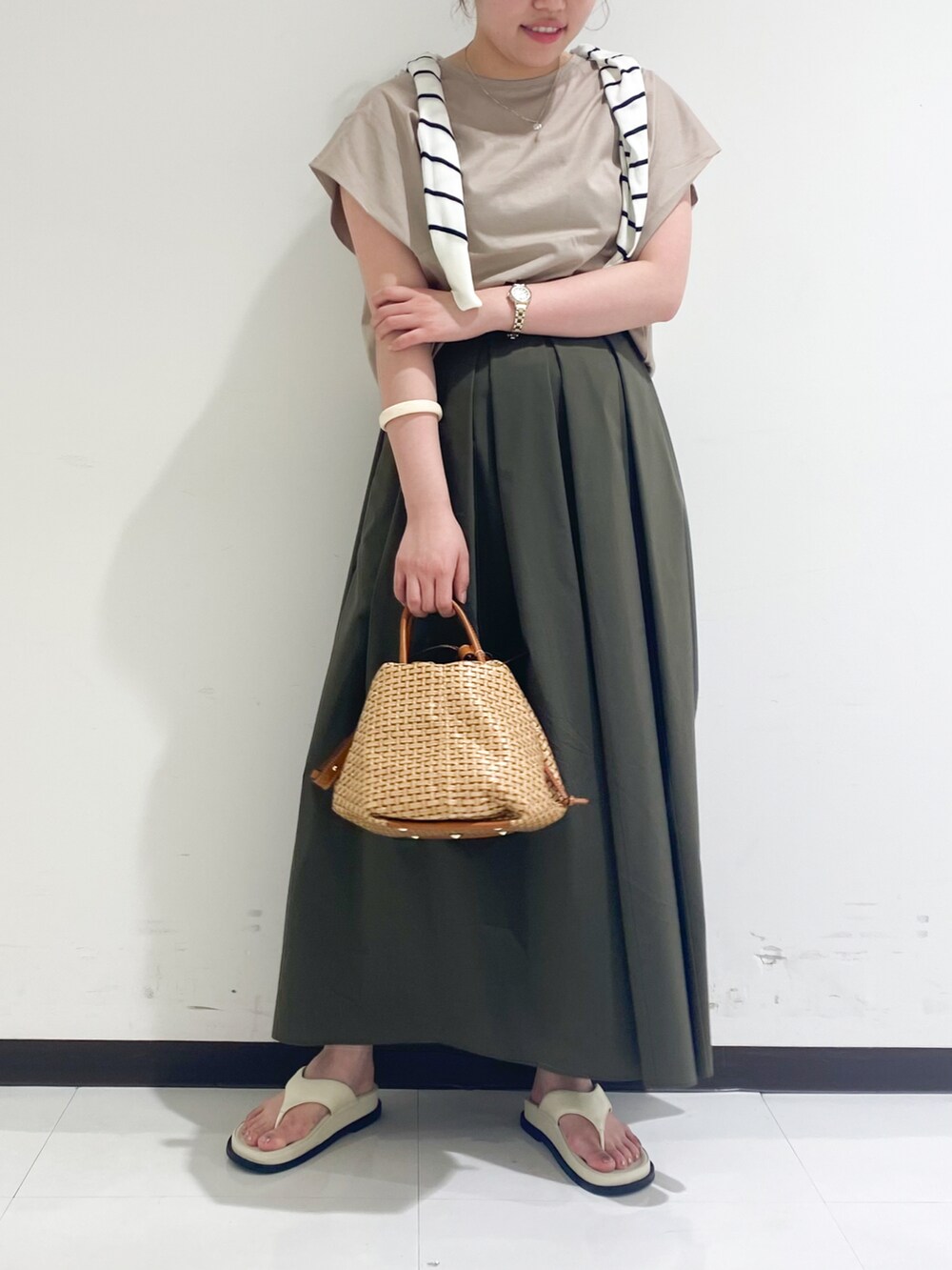 ベージュ系のTシャツ/カットソー、グリーン系のスカート、ブラック系のサンダルを着用したレディースの春コーディネートの3枚目の写真
