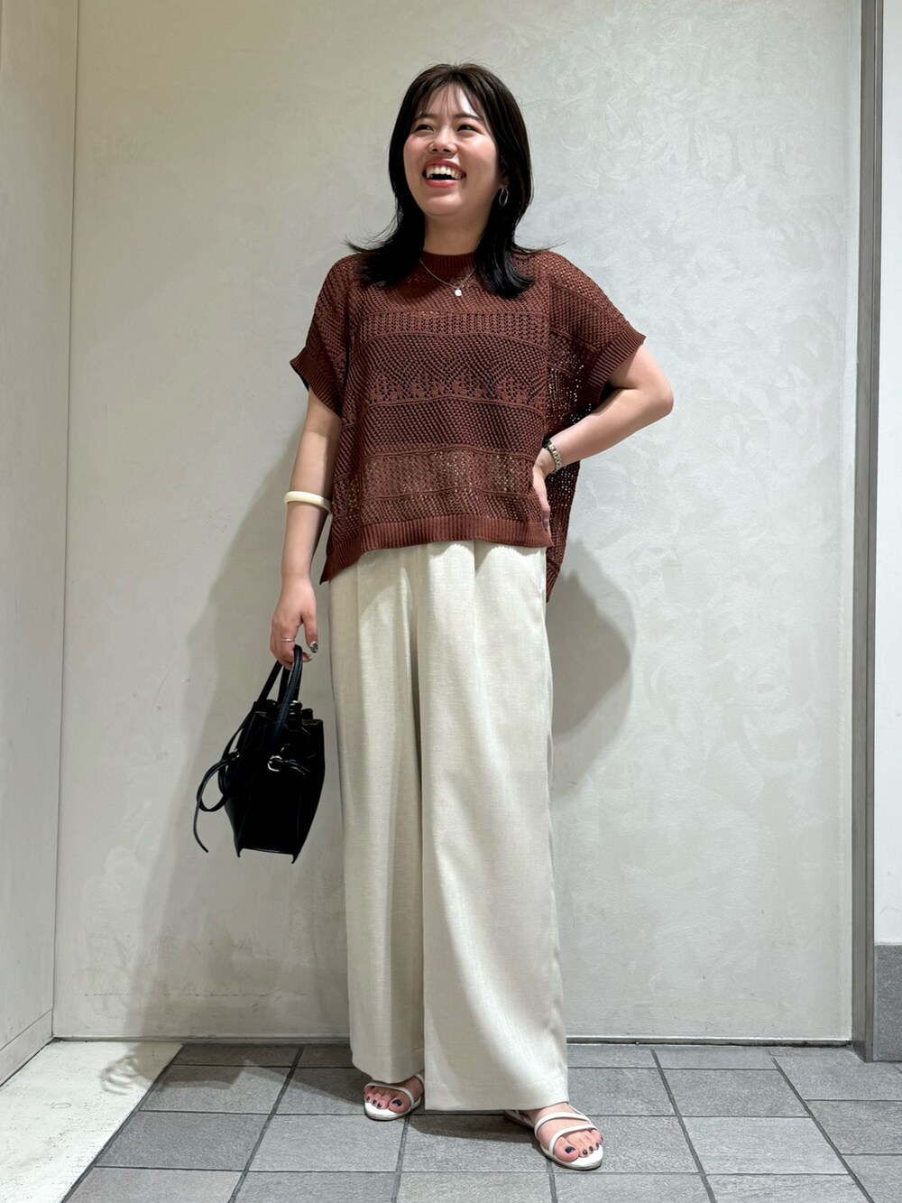 ブラウン系のニット/セーター、ホワイト系のトートバッグを着用したレディースの夏コーディネートの4枚目の写真