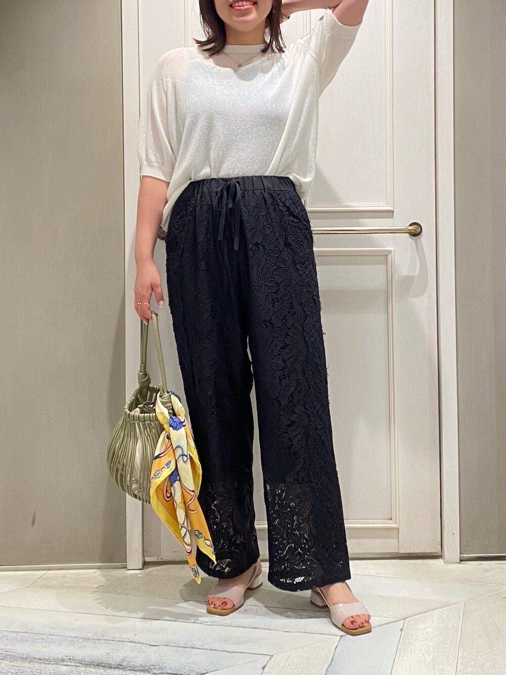 ホワイト系のニット/セーター、ブラック系のその他パンツ、グリーン系のショルダーバッグを着用したレディースの夏コーディネートの3枚目の写真