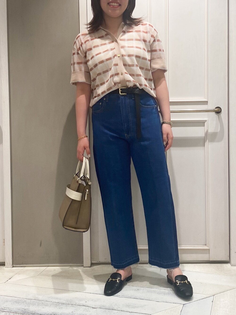 ベージュ系のニット/セーター、ベージュ系のショルダーバッグ、ブルー系のデニムパンツを着用したレディースの春コーディネートの7枚目の写真