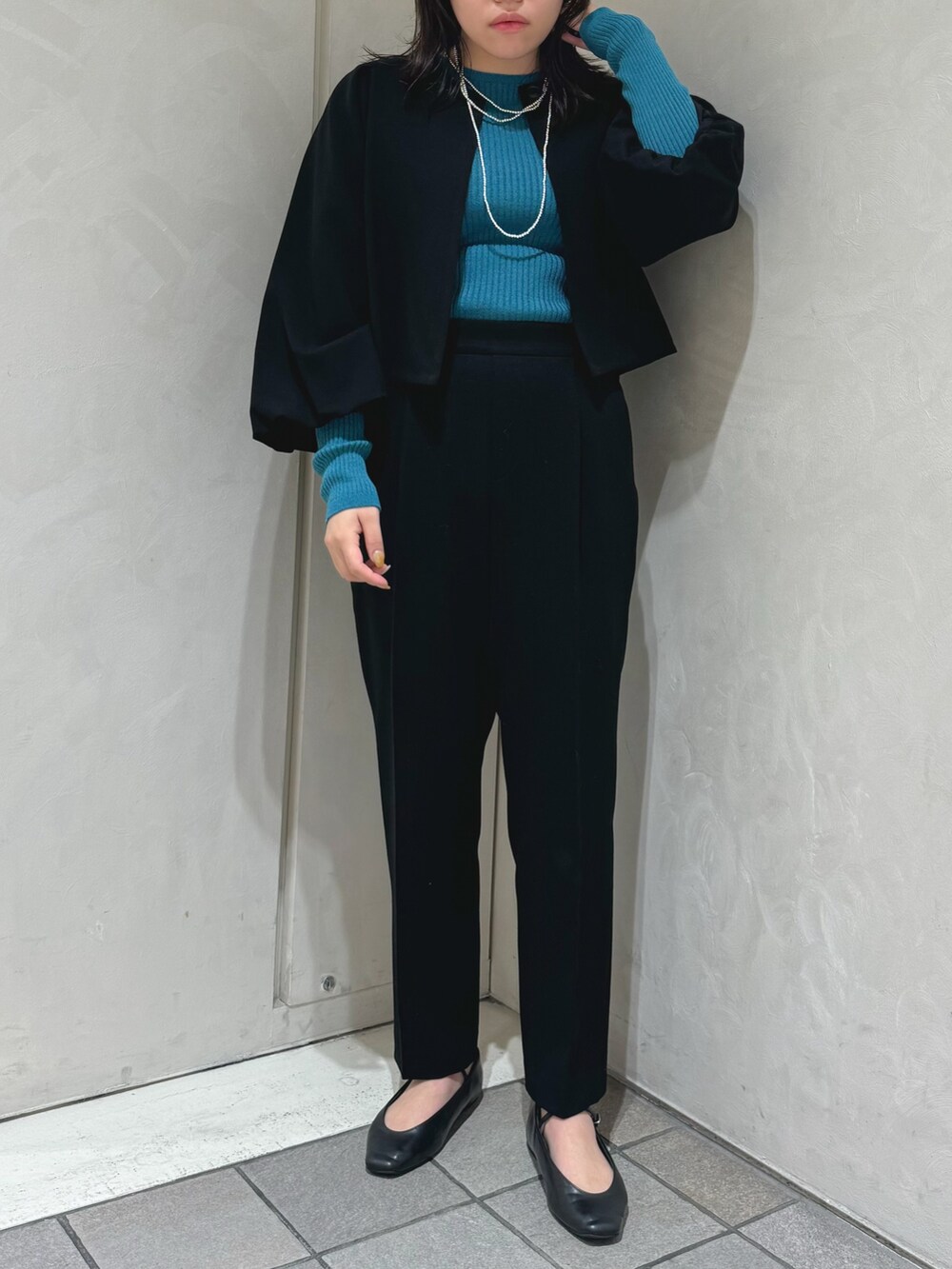 ブラック系のテーラードジャケット、ブルー系のニット/セーター、ブラック系のスラックスを着用したレディースの秋コーディネートの3枚目の写真