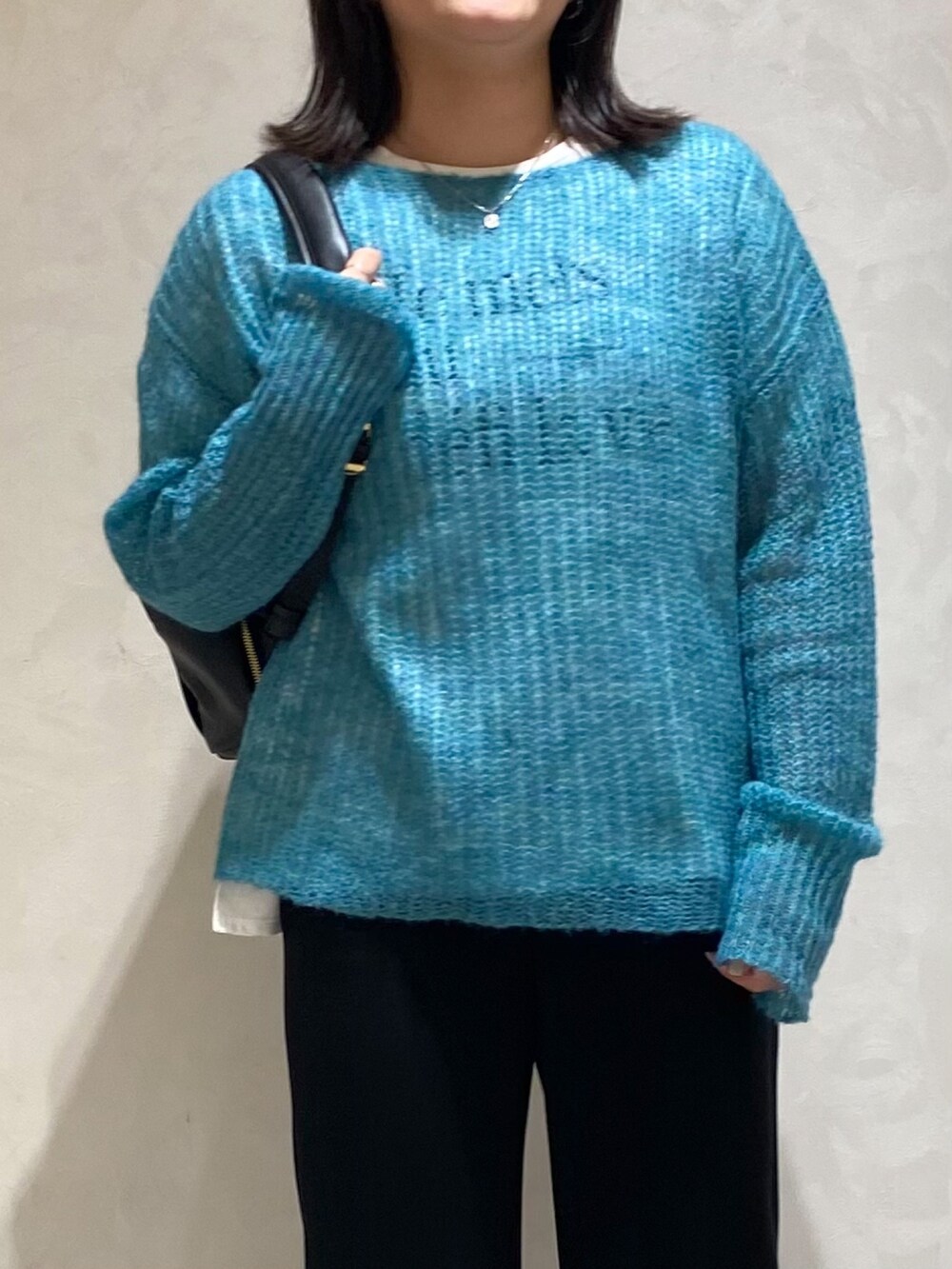 グリーン系のニット/セーター、ブラック系のスラックス、ブラック系のバックパック/リュックを着用したレディースの秋コーディネートの3枚目の写真