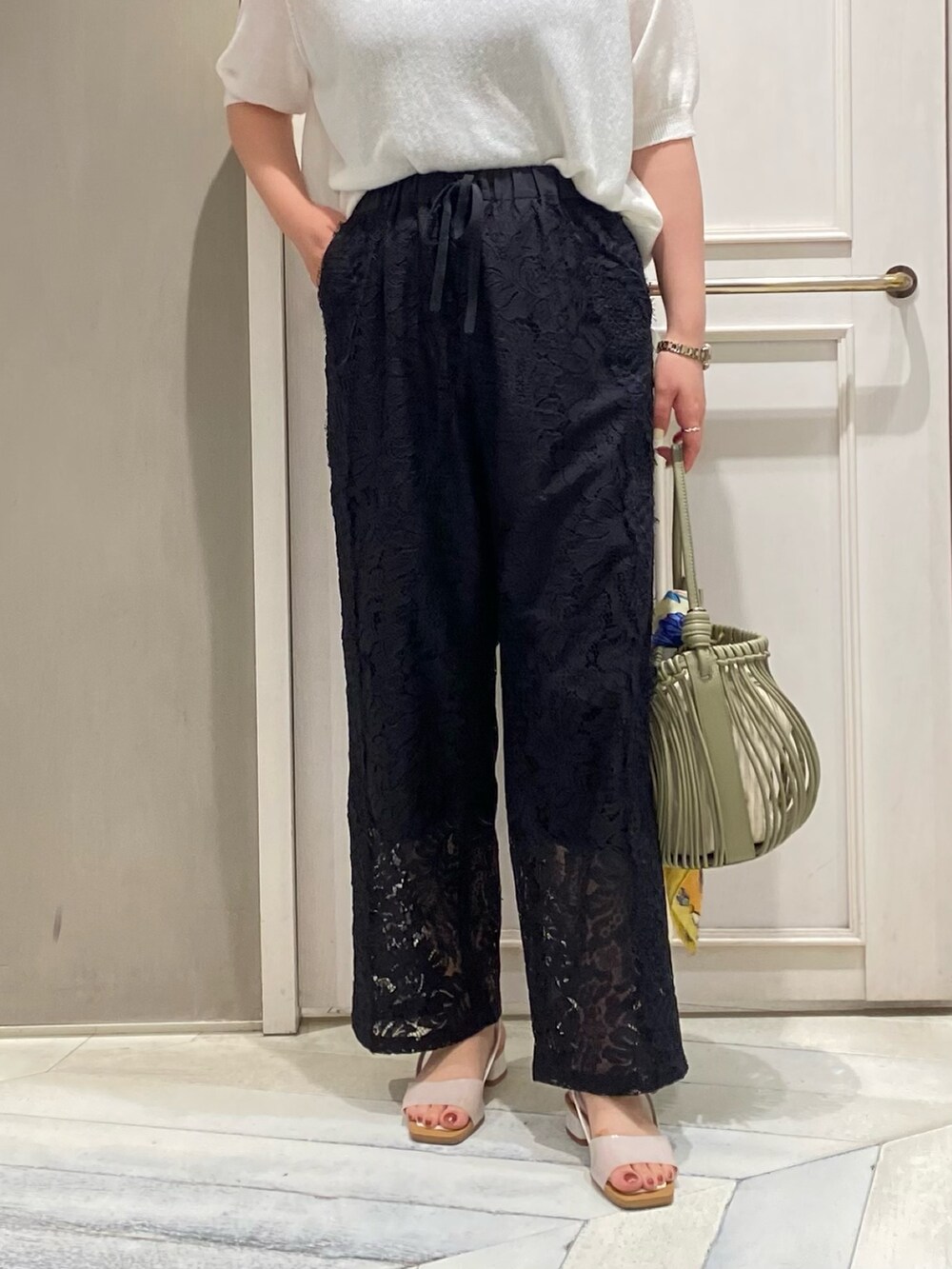 ホワイト系のニット/セーター、ブラック系のその他パンツ、グリーン系のショルダーバッグを着用したレディースの夏コーディネートの6枚目の写真