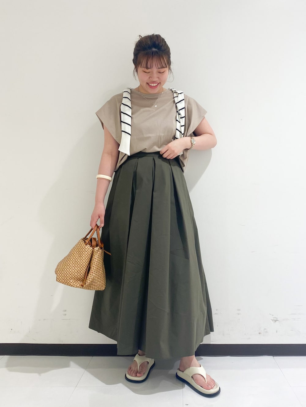 ベージュ系のTシャツ/カットソー、グリーン系のスカート、ブラック系のサンダルを着用したレディースの春コーディネートの4枚目の写真