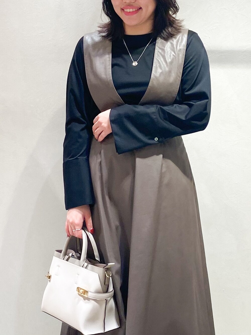 ブラウン系のジャンパースカート、ブラック系のTシャツ/カットソー、ホワイト系のショルダーバッグを着用したレディースの秋コーディネートの4枚目の写真
