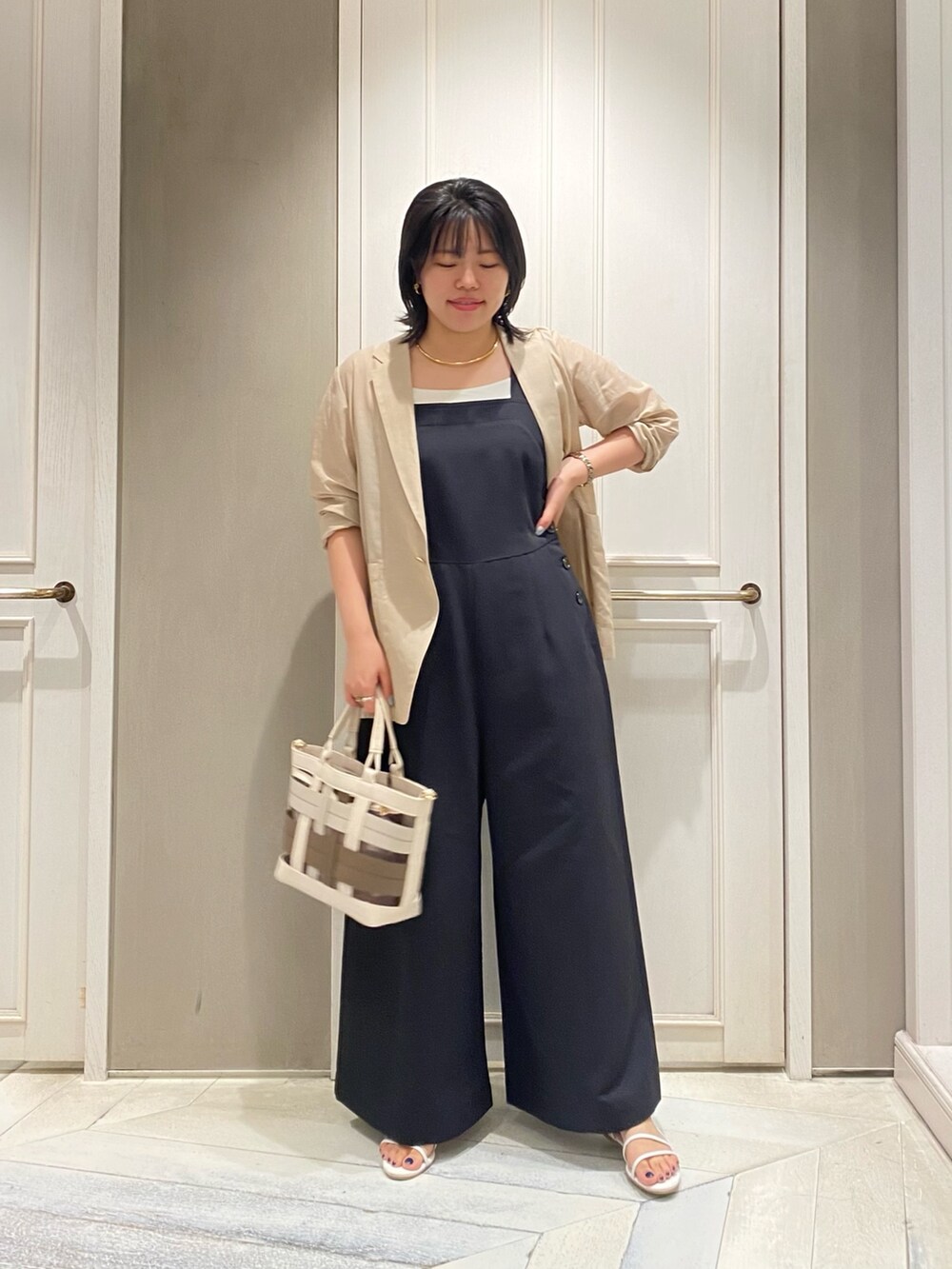 ブラック系のつなぎ/オールインワン、ベージュ系のテーラードジャケット、ベージュ系のハンドバッグを着用したレディースの夏コーディネートの2枚目の写真