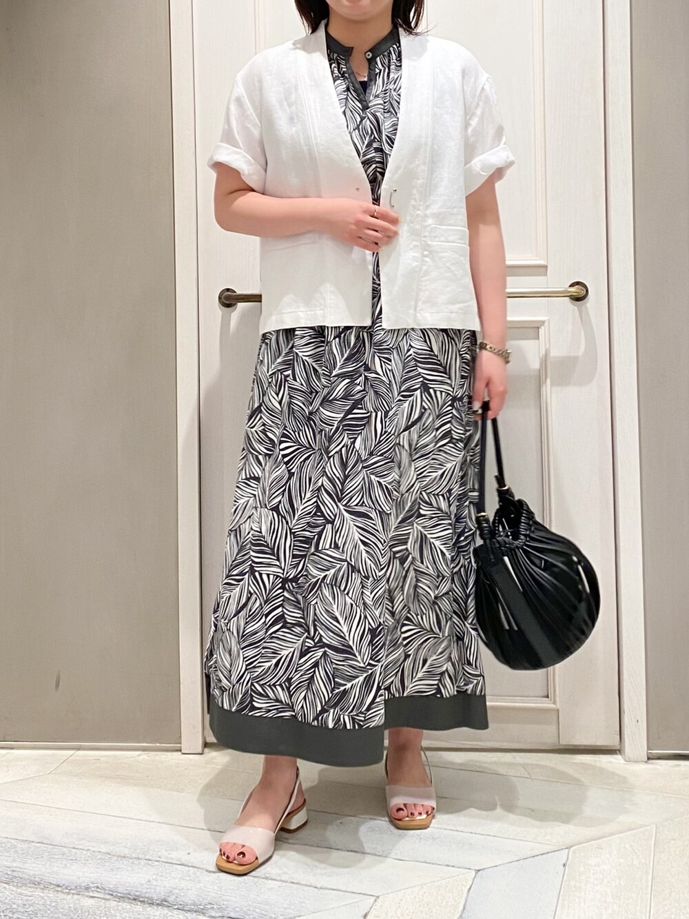 ホワイト系のノーカラージャケット、グレー系のワンピース、ホワイト系のショルダーバッグを着用したレディースの春コーディネートの3枚目の写真