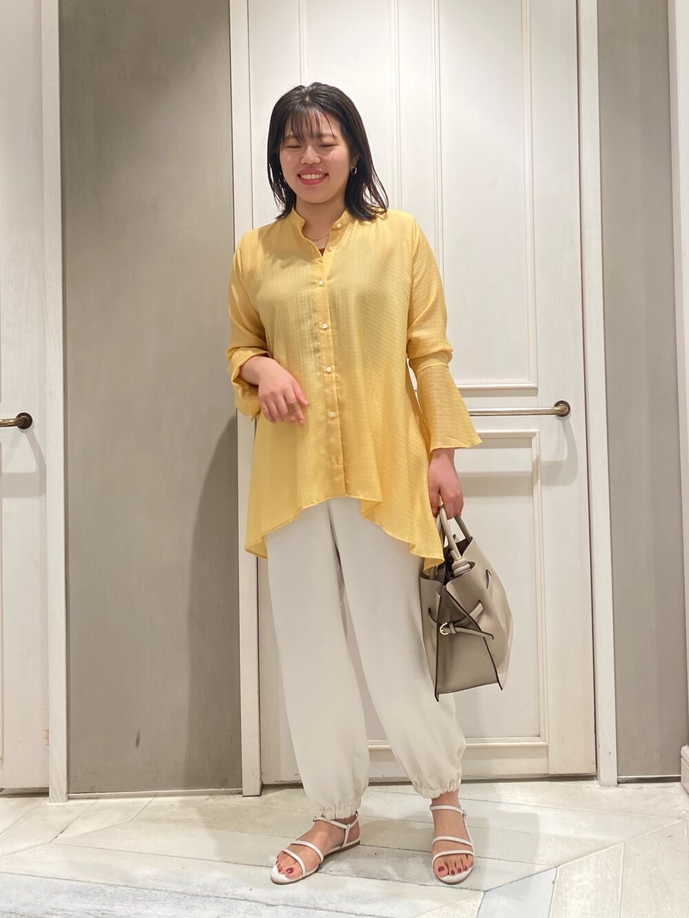 イエロー系のシャツ/ブラウス、ホワイト系のその他パンツ、ベージュ系のハンドバッグを着用したレディースの夏コーディネートの3枚目の写真
