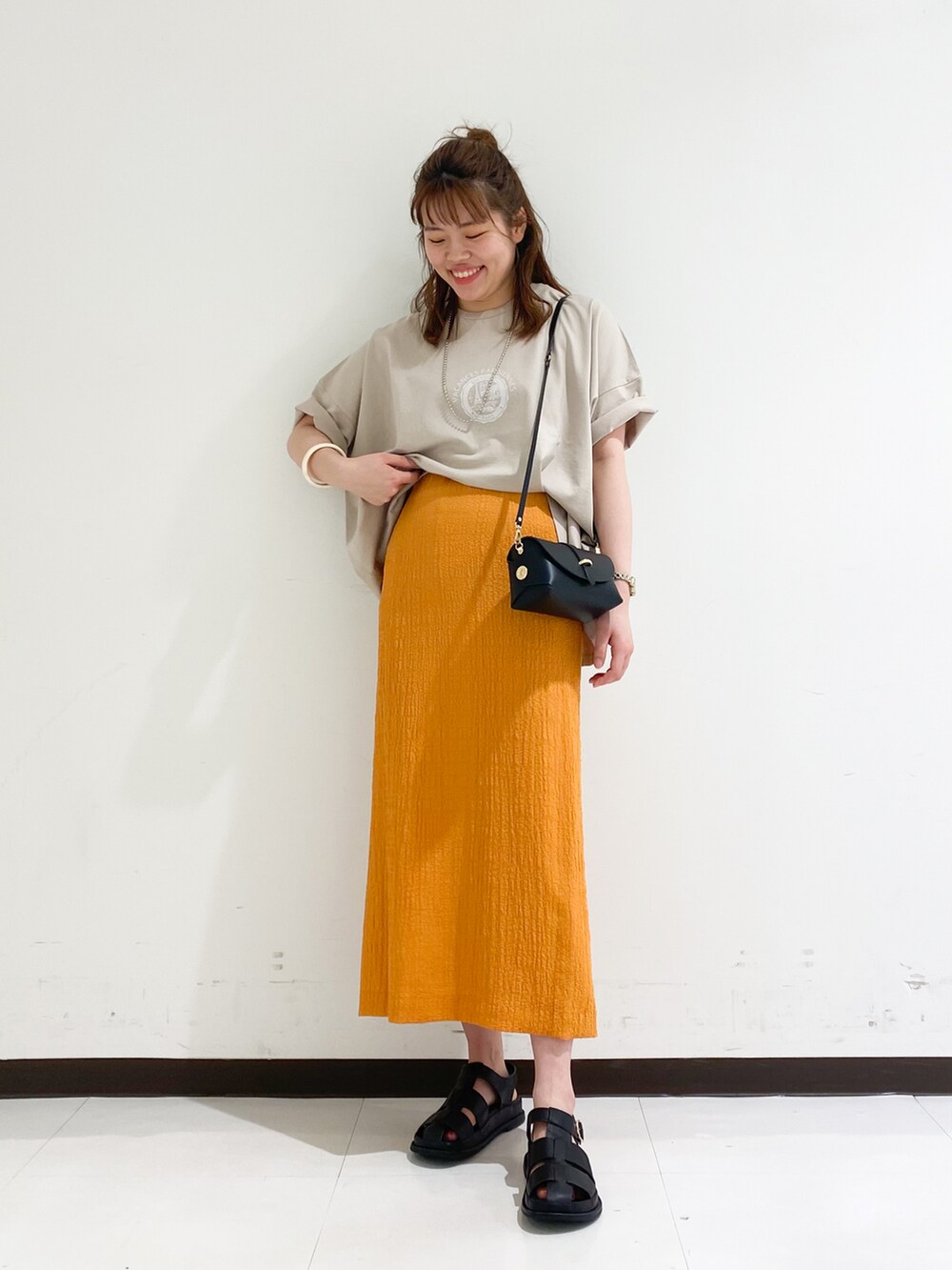 ベージュ系のTシャツ/カットソー、ブラック系のスカート、ブラック系のショルダーバッグを着用したレディースの春コーディネートの2枚目の写真