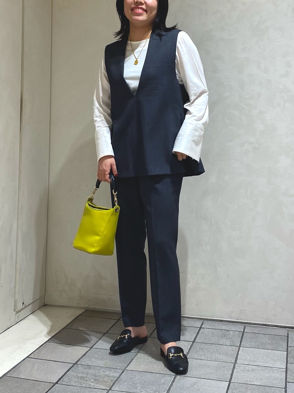 グレー系のベスト、グレー系のスラックス、ホワイト系のTシャツ/カットソーを着用したレディースの秋コーディネートの2枚目の写真