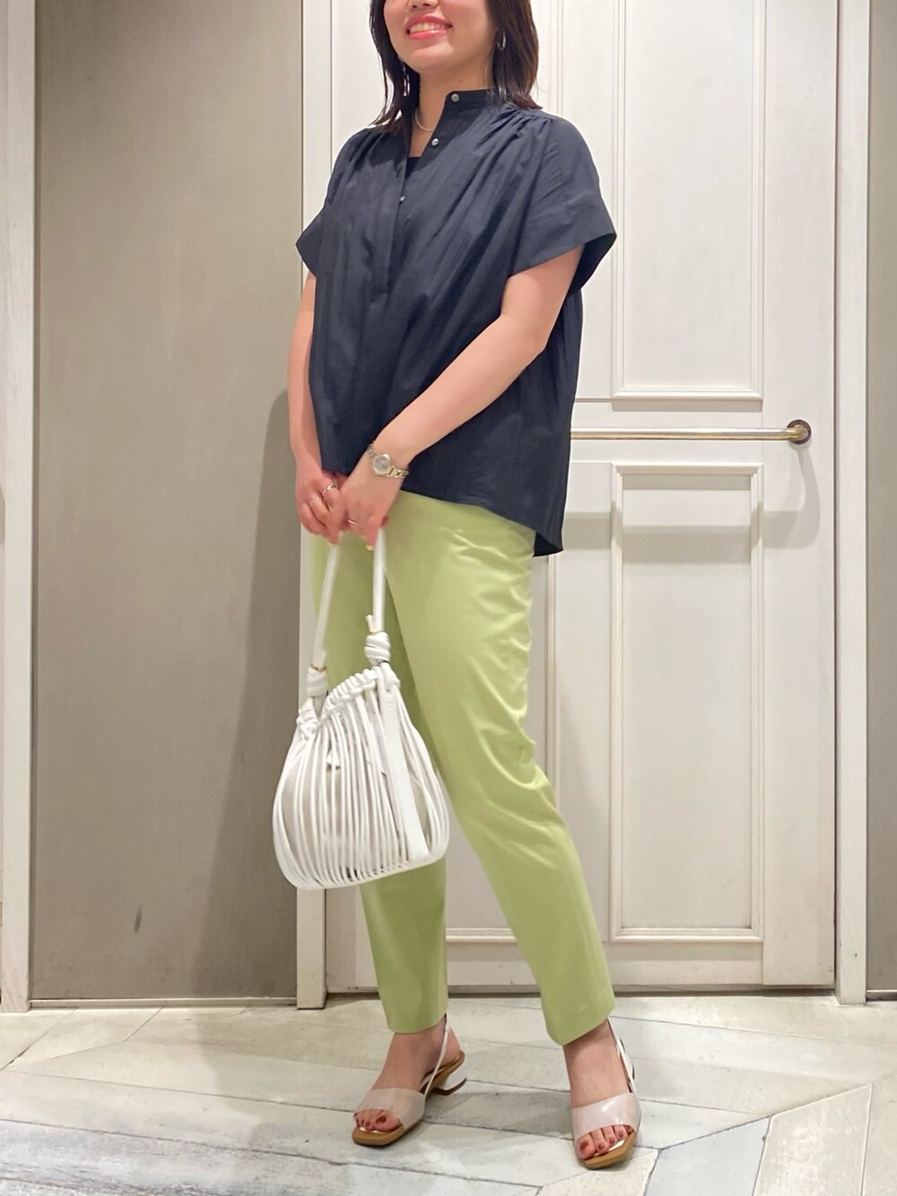 ブラック系のシャツ/ブラウス、グリーン系のスラックス、ホワイト系のサンダルを着用したレディースの夏コーディネートの2枚目の写真