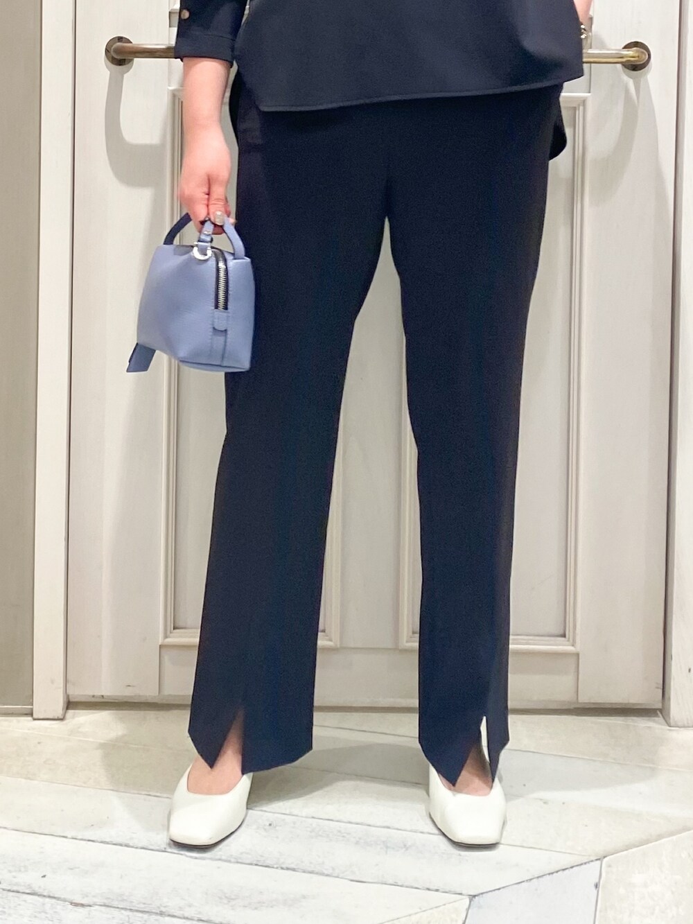 ブラック系のシャツ/ブラウス、ブラック系のスラックス、ブルー系のハンドバッグを着用したレディースの春コーディネートの3枚目の写真