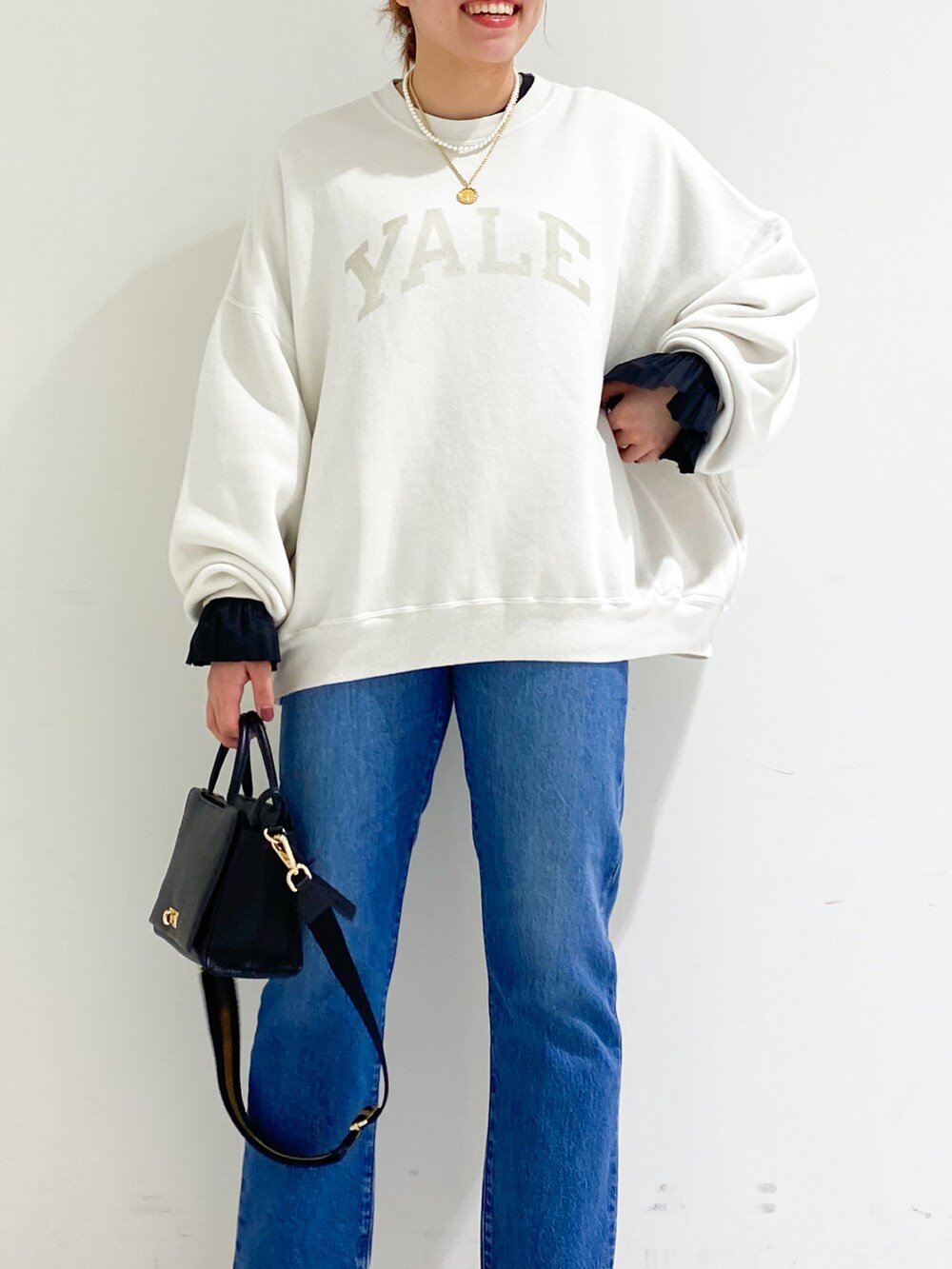 ホワイト系のスウェット、ブラウン系のハンドバッグ、ブラック系のパンプスを着用したレディースの秋コーディネートの5枚目の写真