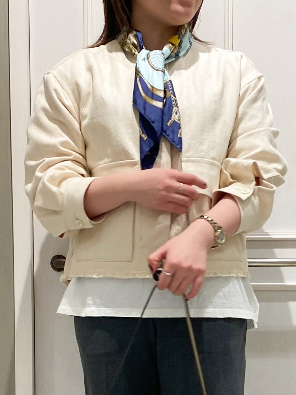 ホワイト系のブルゾン、ホワイト系のショルダーバッグ、グレー系のスラックスを着用したレディースの冬コーディネートの3枚目の写真