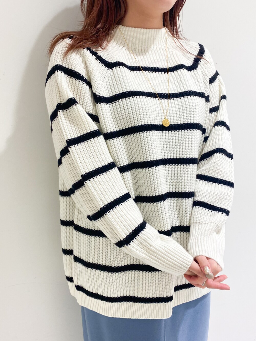 ホワイト系のニット/セーター、ブルー系のスカート、ブラック系のブーツを着用したレディースの冬コーディネートの3枚目の写真