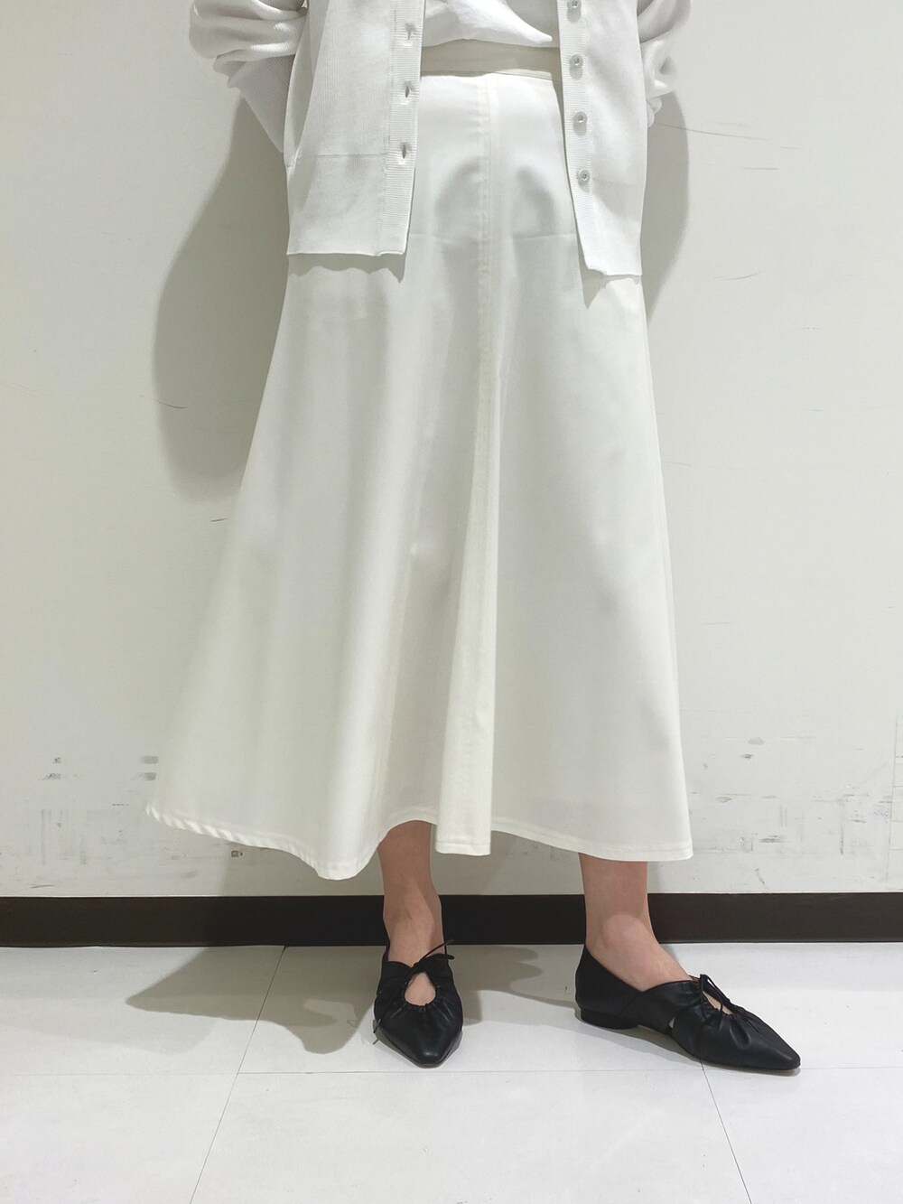 ホワイト系のカーディガン/ボレロ、ホワイト系のスカート、ブラック系のトートバッグを着用したレディースの春コーディネートの4枚目の写真