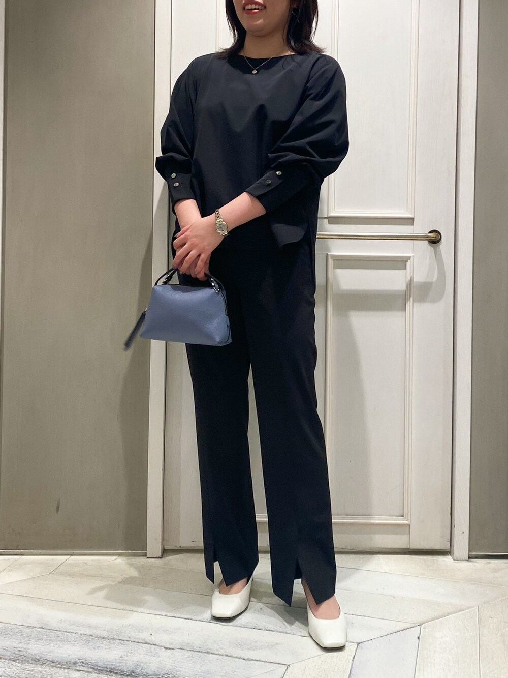 ブラック系のシャツ/ブラウス、ブラック系のスラックス、ブルー系のハンドバッグを着用したレディースの春コーディネートの4枚目の写真