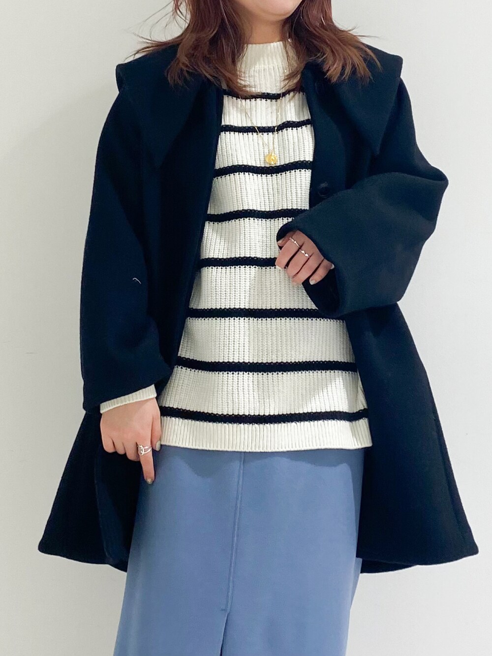 ブラック系のチェスターコート、ブラック系のブーツ、ブルー系のスカートを着用したレディースの冬コーディネートの4枚目の写真