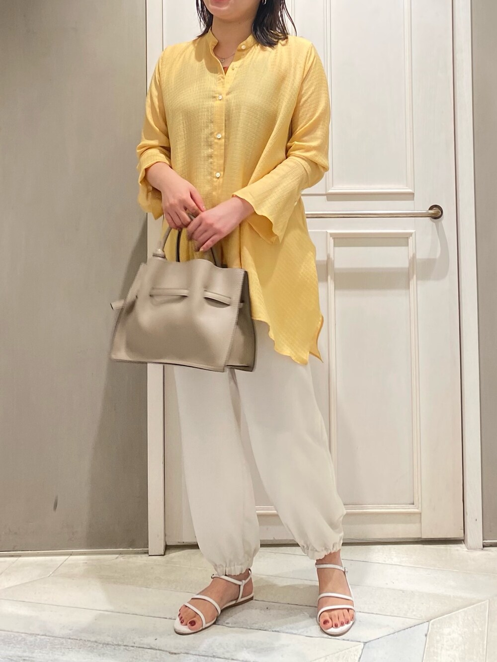 イエロー系のシャツ/ブラウス、ホワイト系のその他パンツ、ベージュ系のハンドバッグを着用したレディースの夏コーディネートの2枚目の写真