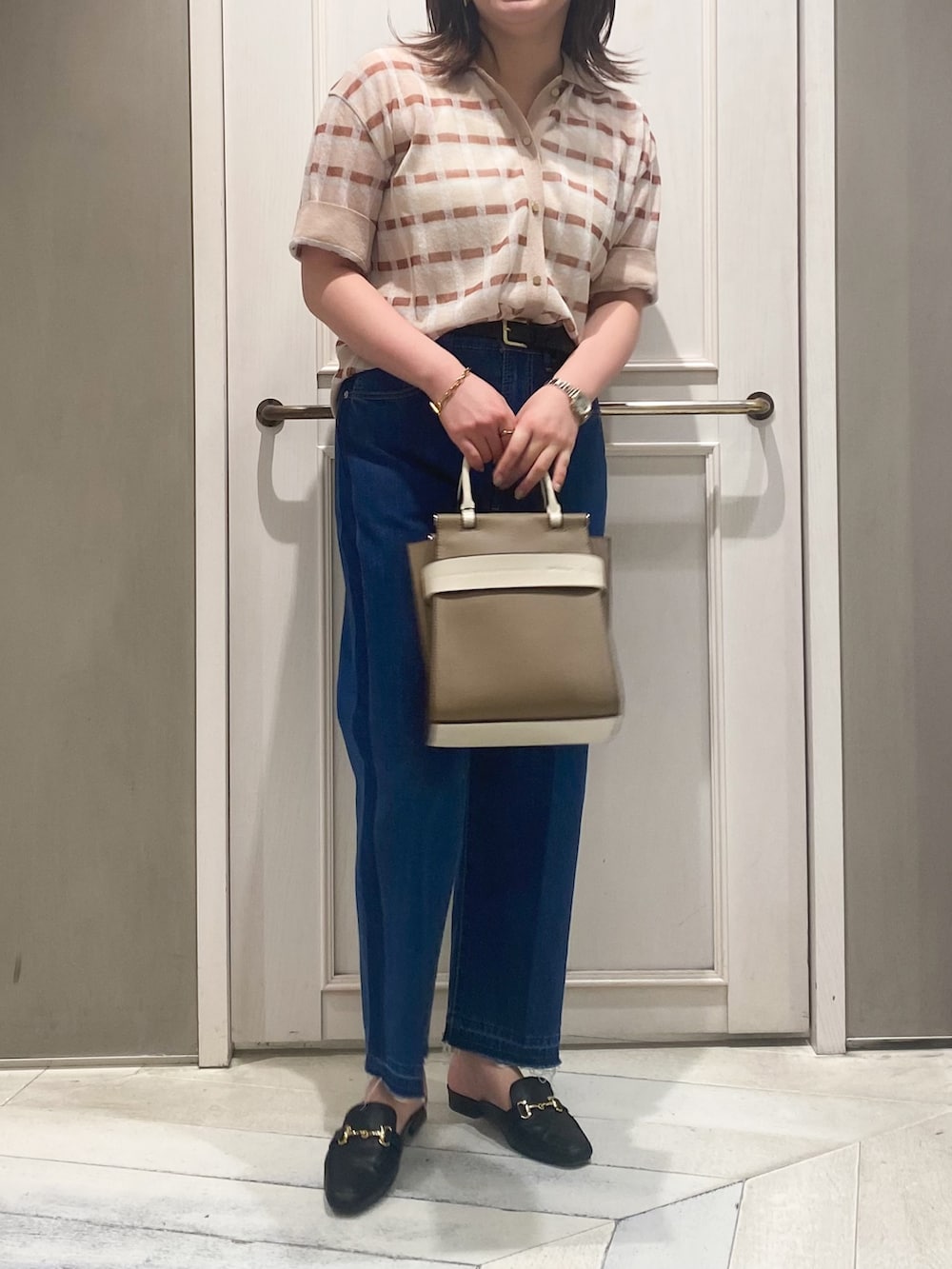 ベージュ系のニット/セーター、ベージュ系のショルダーバッグ、ブルー系のデニムパンツを着用したレディースの春コーディネートの5枚目の写真