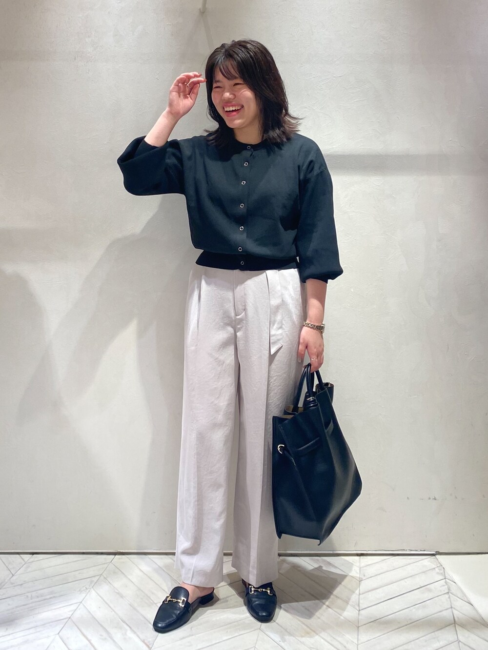 ブラック系のカーディガン/ボレロ、ピンク系のスラックス、ブラック系のトートバッグを着用したレディースの秋コーディネートの2枚目の写真