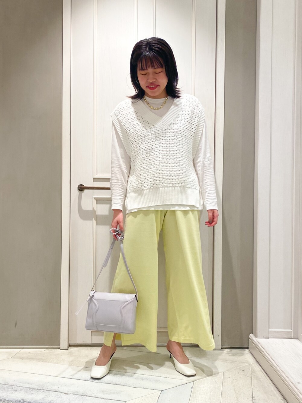 グリーン系のニット/セーター、イエロー系のその他パンツ、パープル系のショルダーバッグを着用したレディースの春コーディネートの3枚目の写真