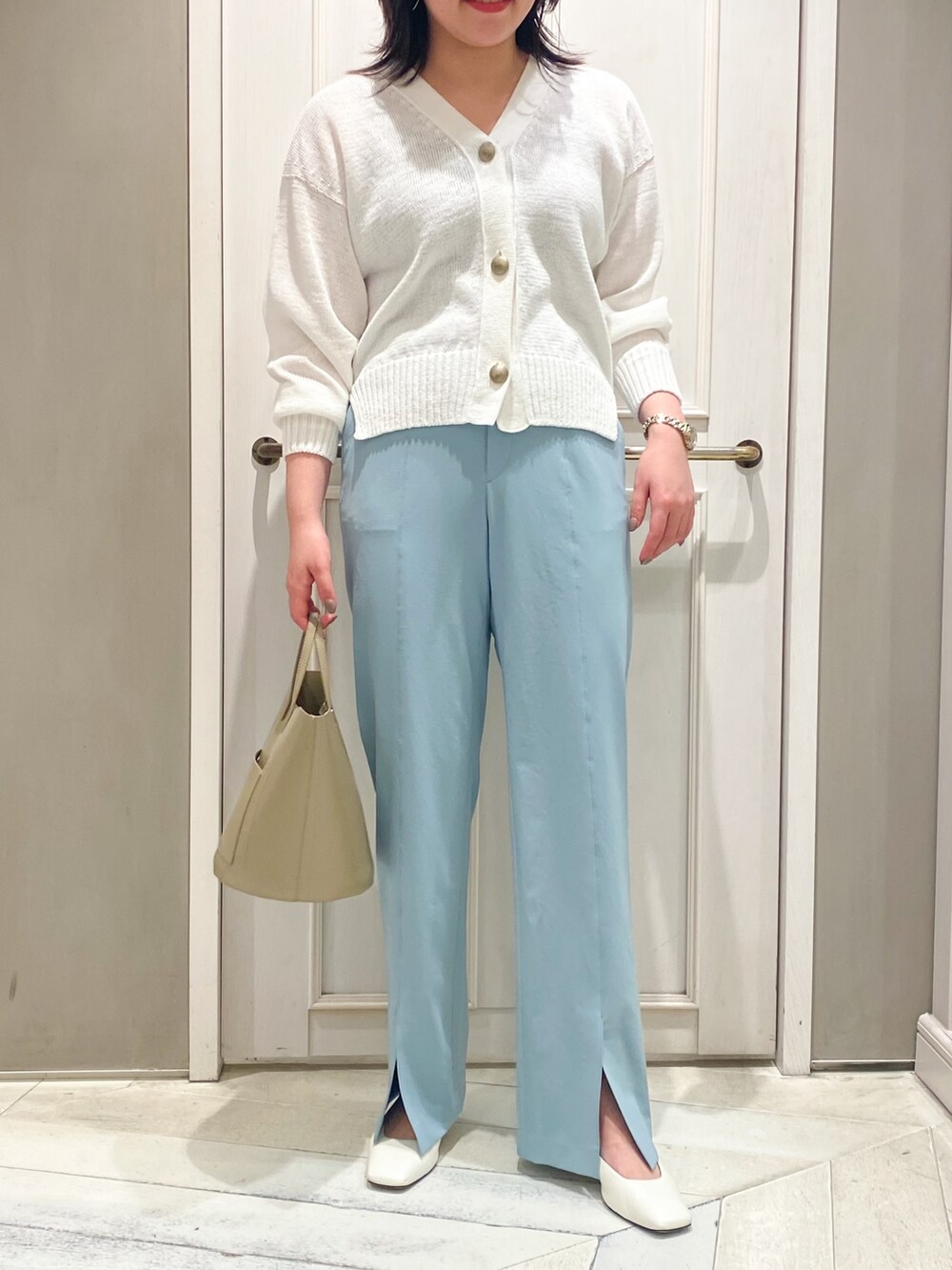 ホワイト系のカーディガン/ボレロ、ベージュ系のハンドバッグ、ブルー系のスラックスを着用したレディースの春コーディネートの3枚目の写真