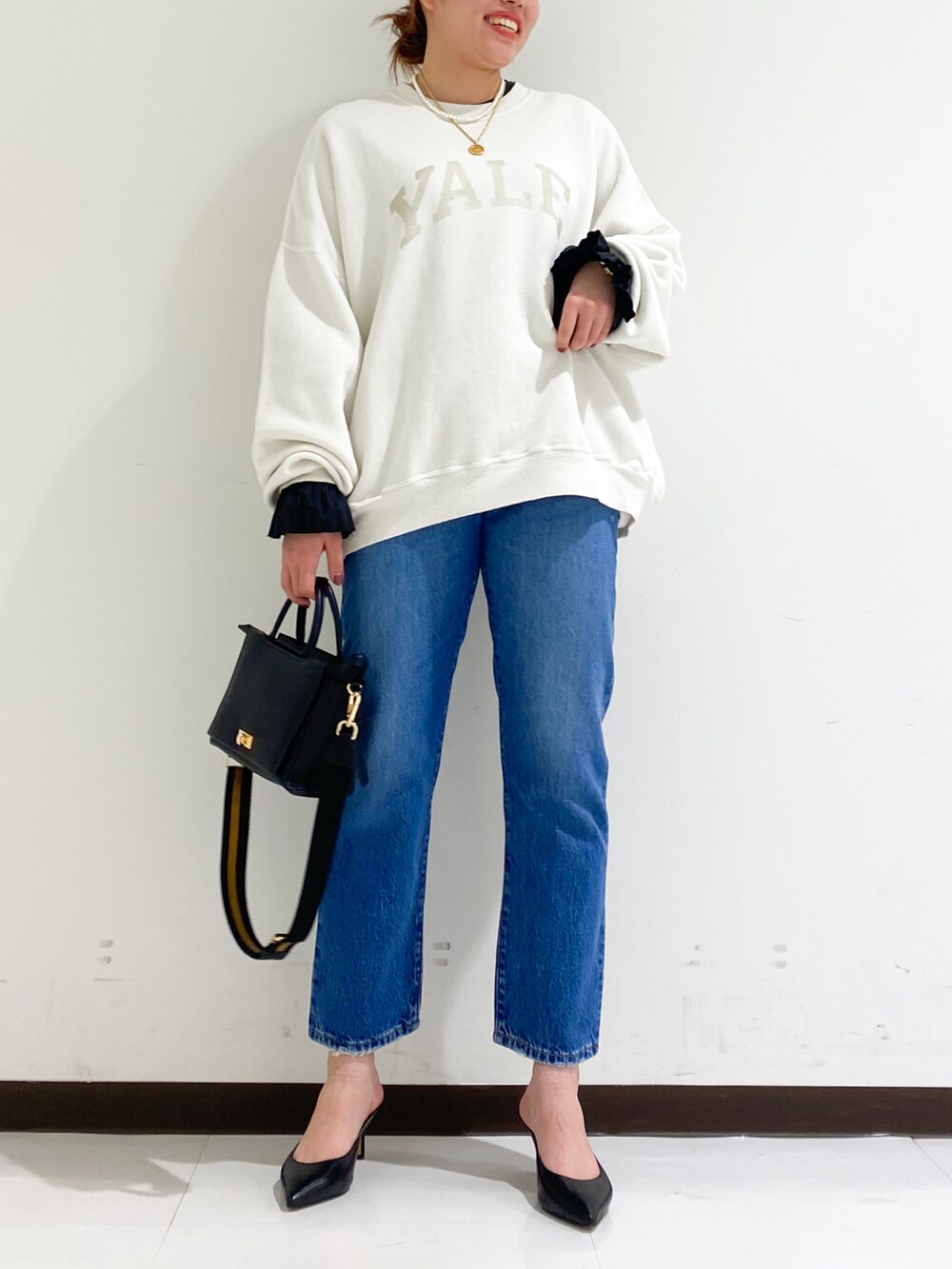 ホワイト系のスウェット、ブラウン系のハンドバッグ、ブラック系のパンプスを着用したレディースの秋コーディネートの2枚目の写真