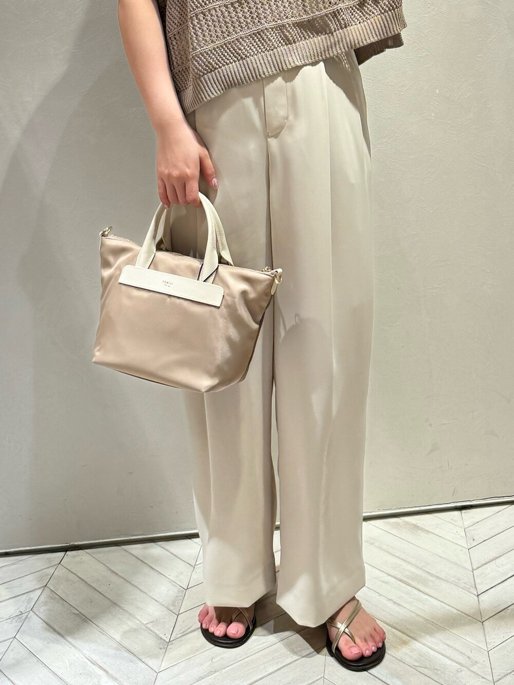 ベージュ系のニット/セーター、ホワイト系のスラックスを着用したレディースの春コーディネートの2枚目の写真