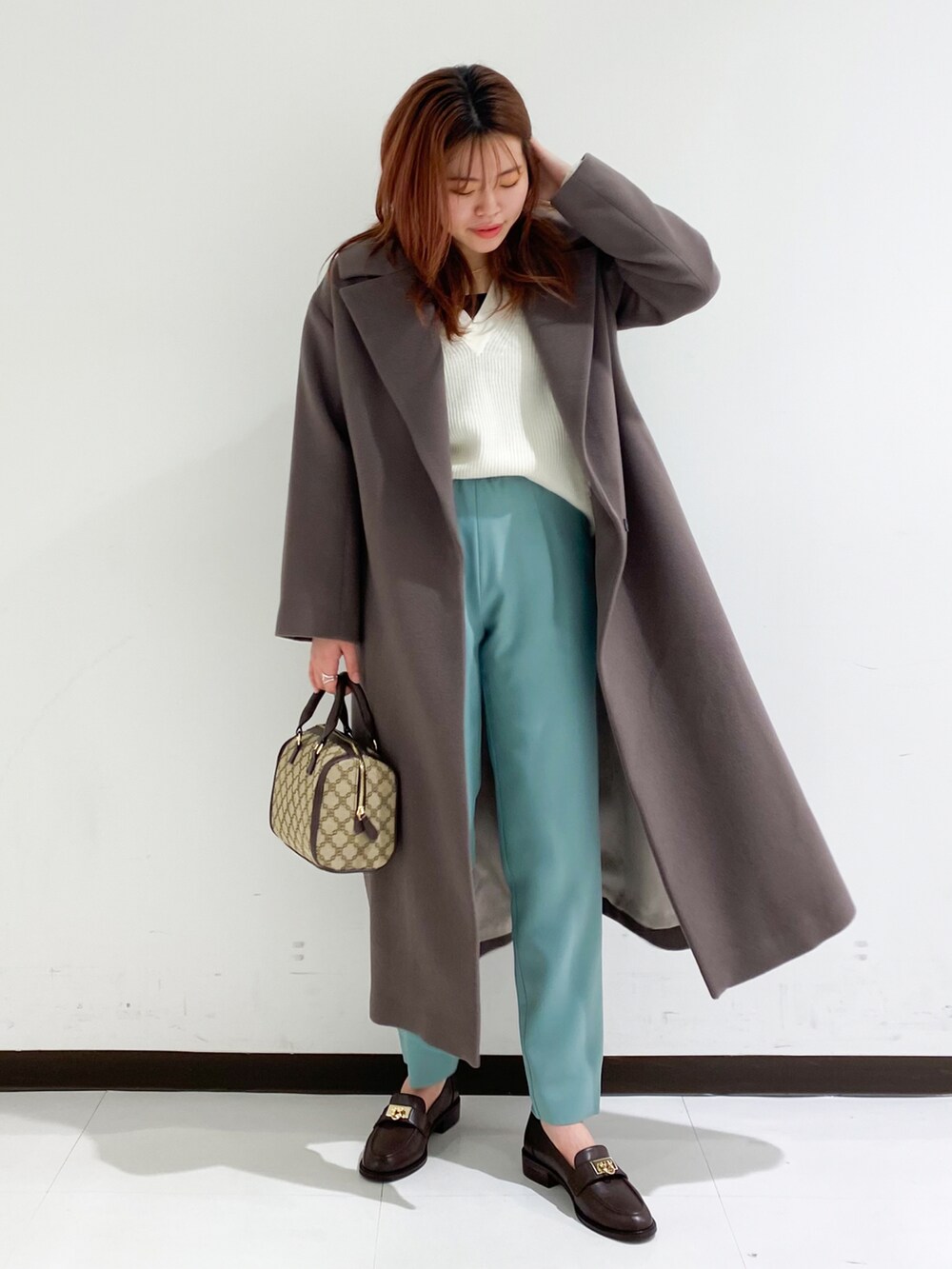 グリーン系のその他パンツ、ホワイト系のニット/セーター、ブラウン系のチェスターコートを着用したレディースの秋コーディネートの2枚目の写真