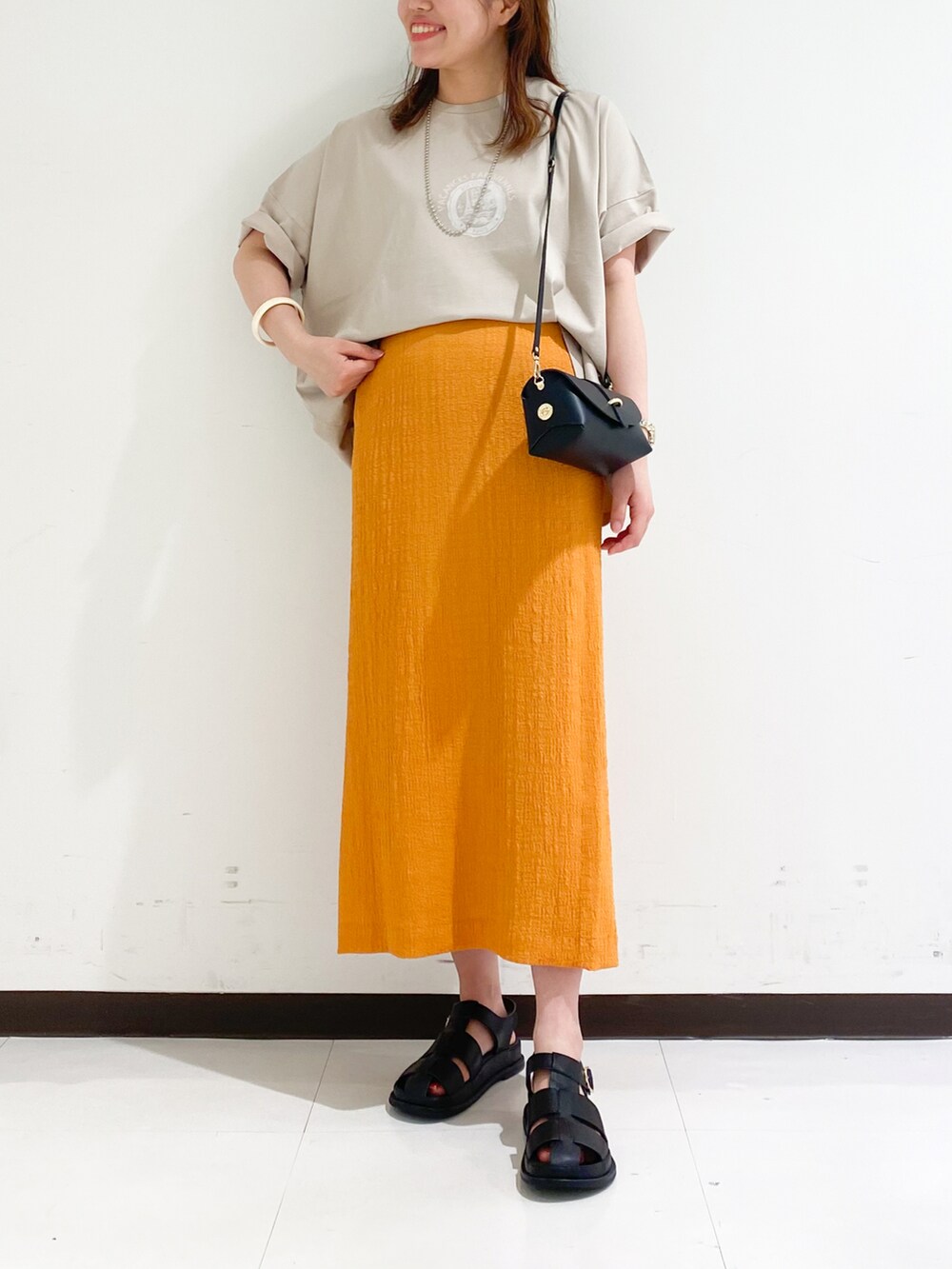 ベージュ系のTシャツ/カットソー、ブラック系のスカート、ブラック系のショルダーバッグを着用したレディースの春コーディネートの5枚目の写真