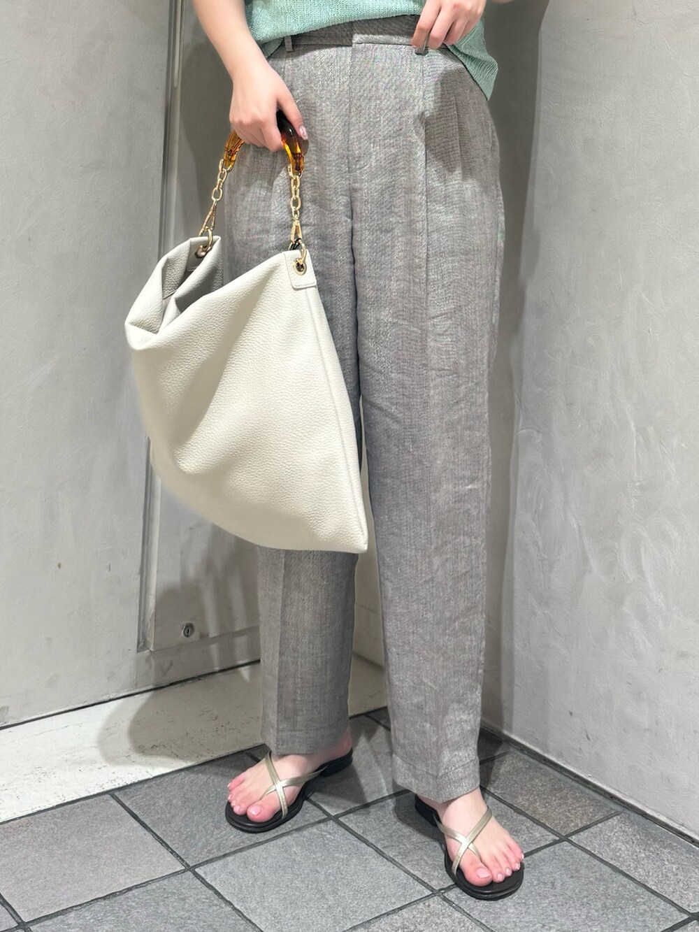 グリーン系のTシャツ/カットソー、グレー系のスラックス、ホワイト系のトートバッグを着用したレディースの夏コーディネートの5枚目の写真